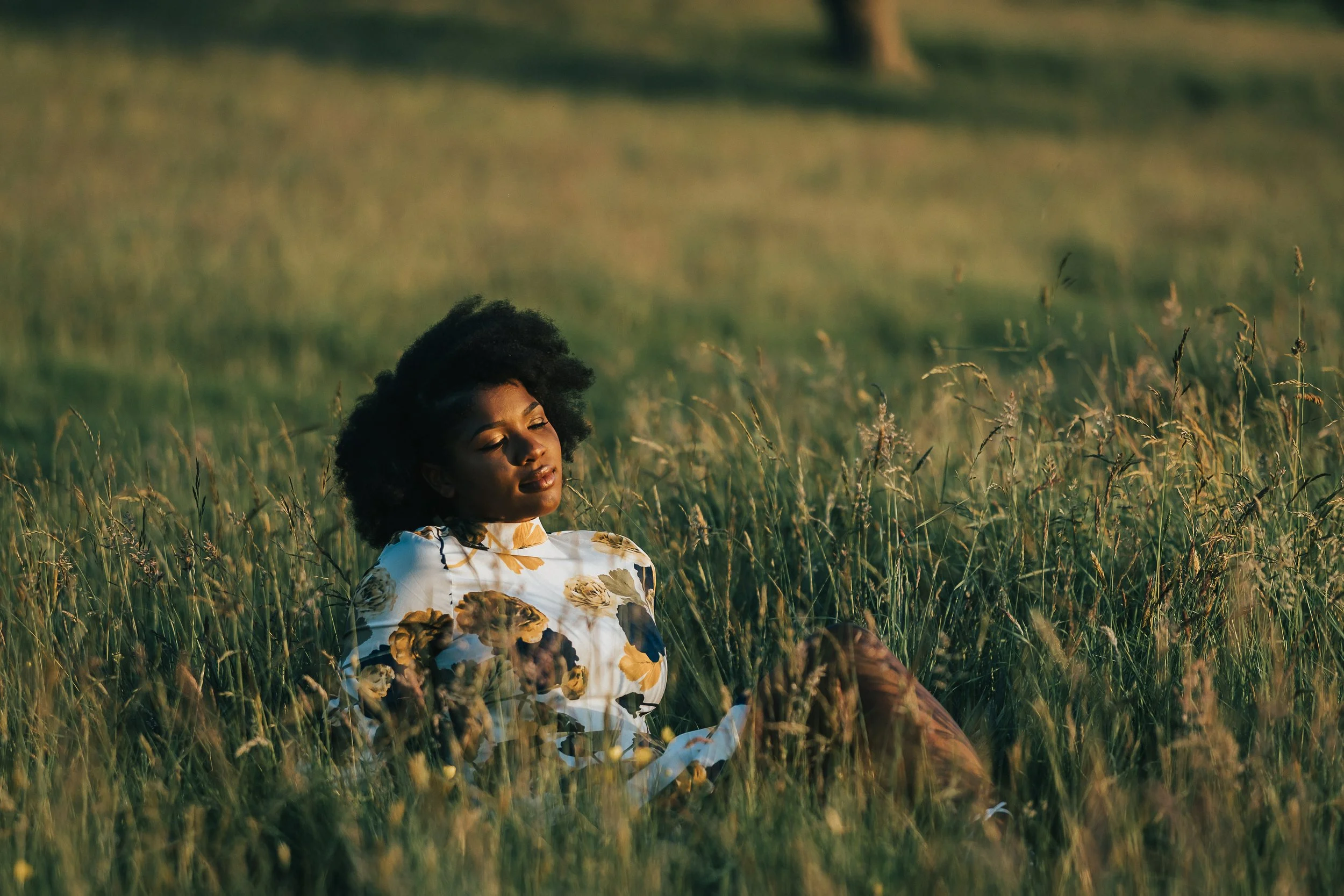 women sits in grass during golden hour