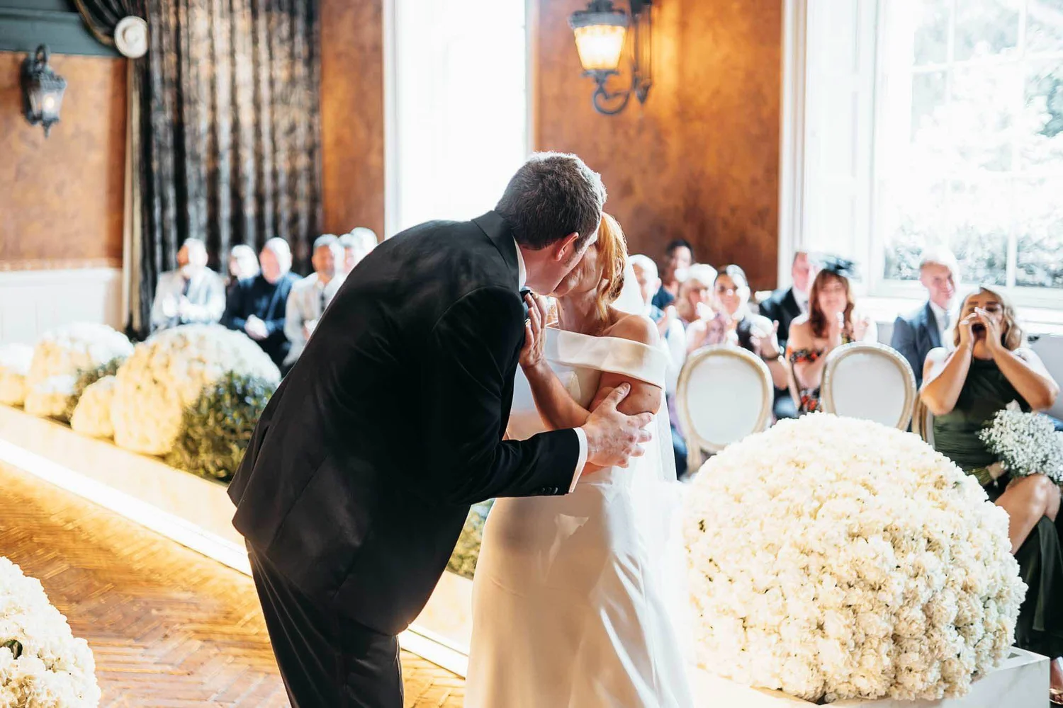 Bride and groom kissing in the daylight-filled Secret Garden Chapel at The Croft Hotel in summer