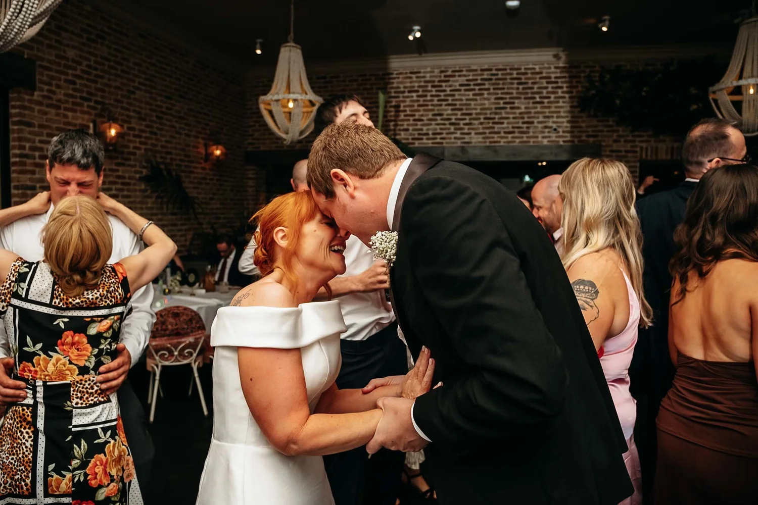 Bride and groom embracing among their guests in the Garden Suite at The Croft Hotel