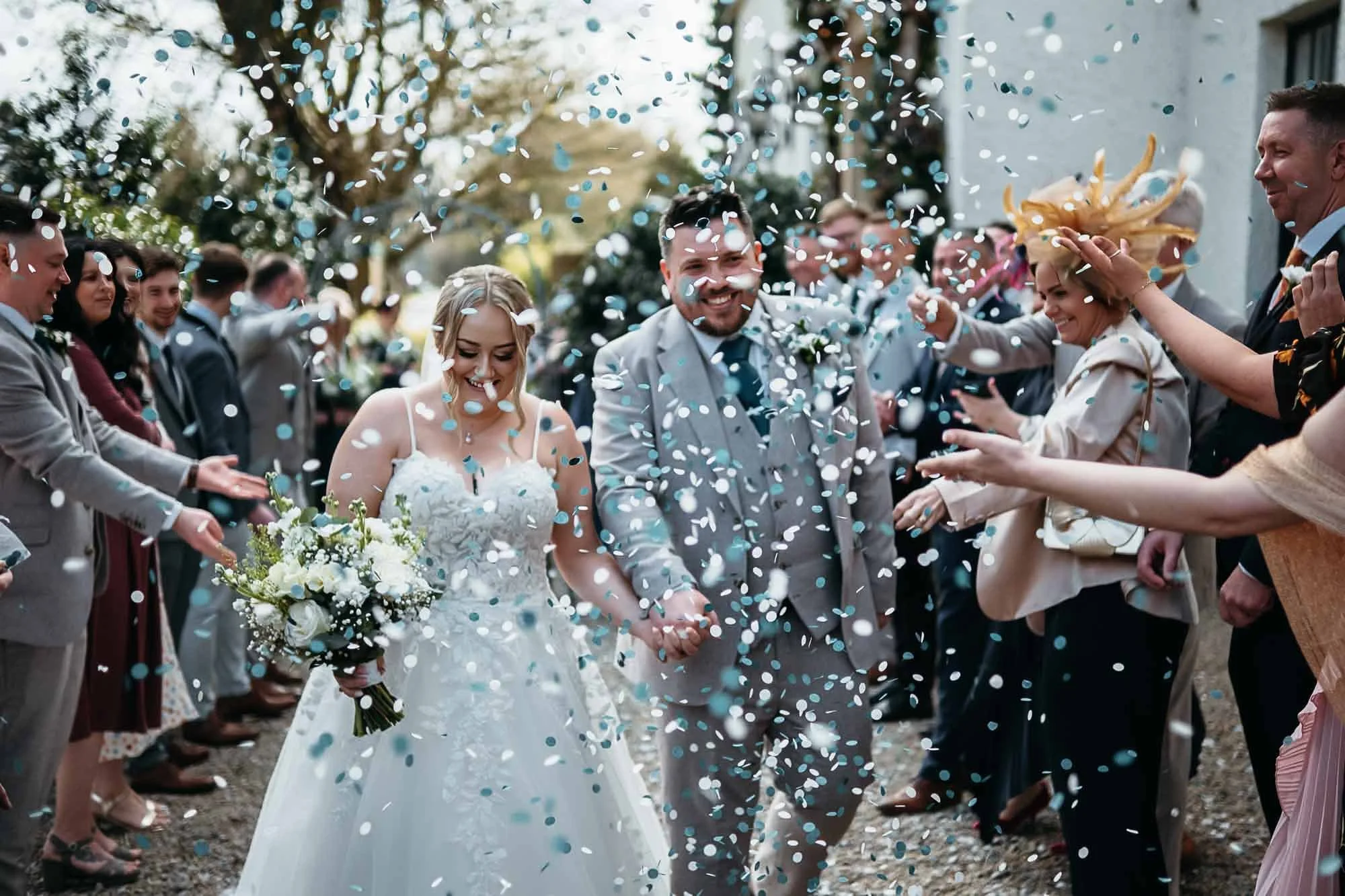 Bride and groom walking through teal and white confetti at The Croft Hotel