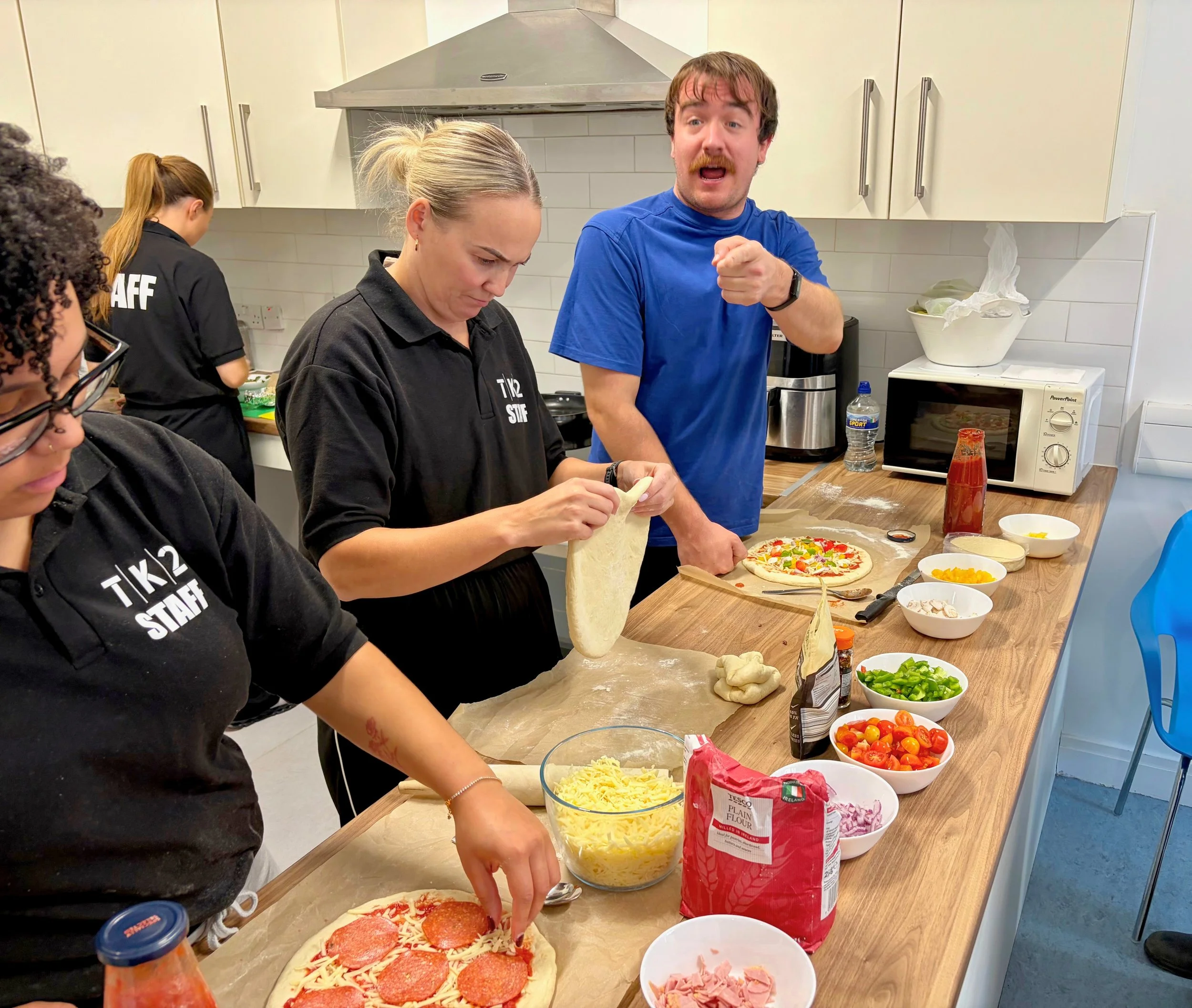 RCR kitchen staff prepare nutritious meals together, rolling out dough with fresh ingredients on the counter