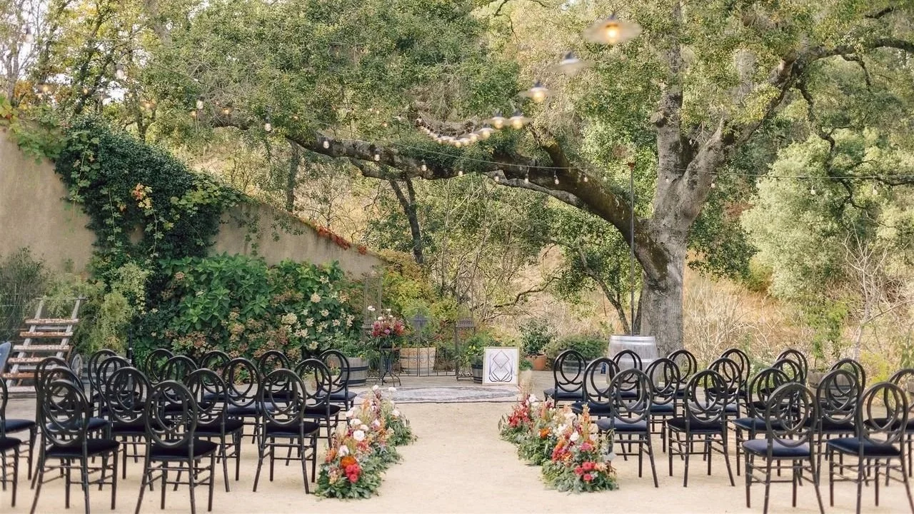 Ceremony aisle beneath an oak tree at a curated wine country wedding venue