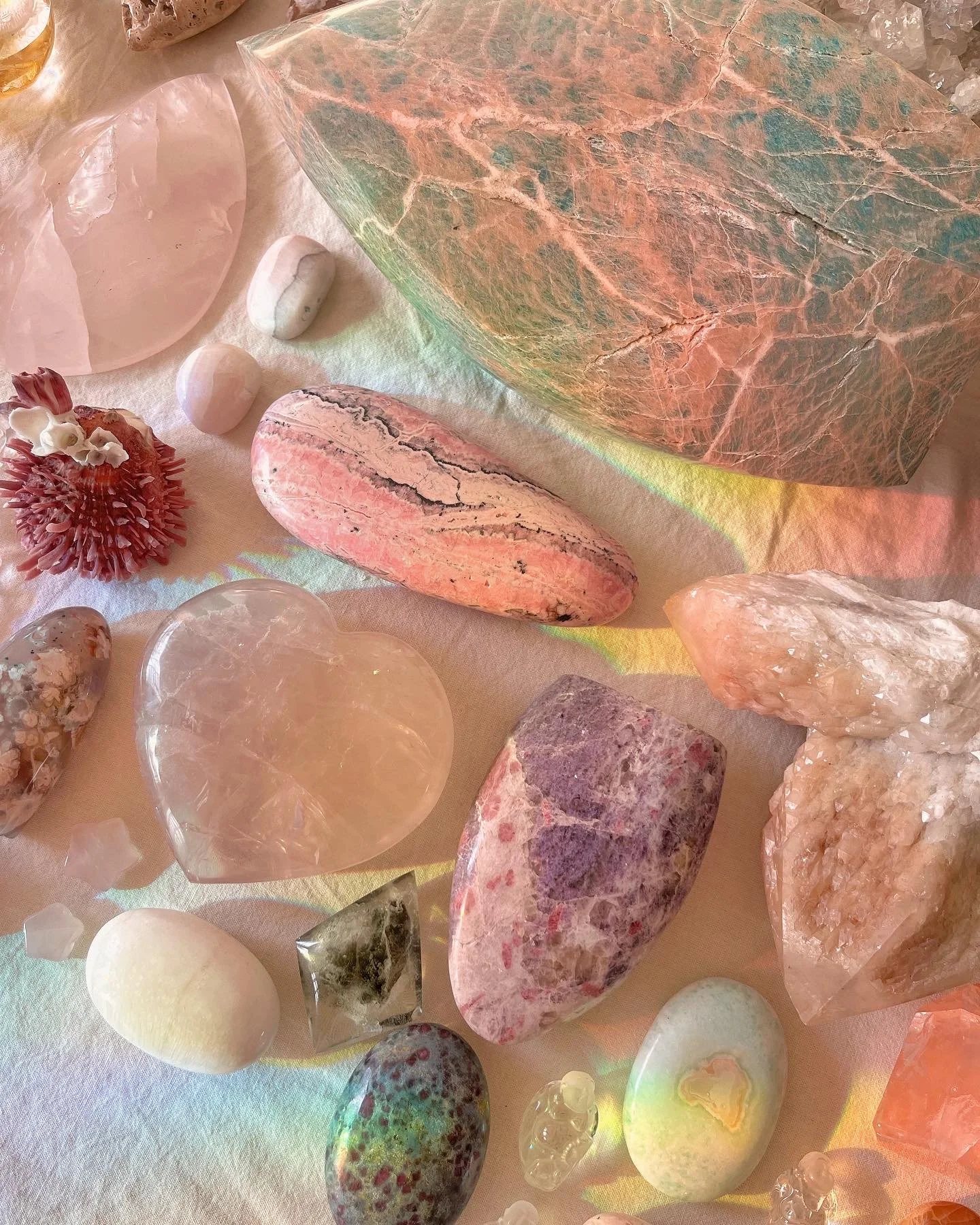 Various colorful and semi-transparent polished and raw gemstones and minerals arranged on a white surface.