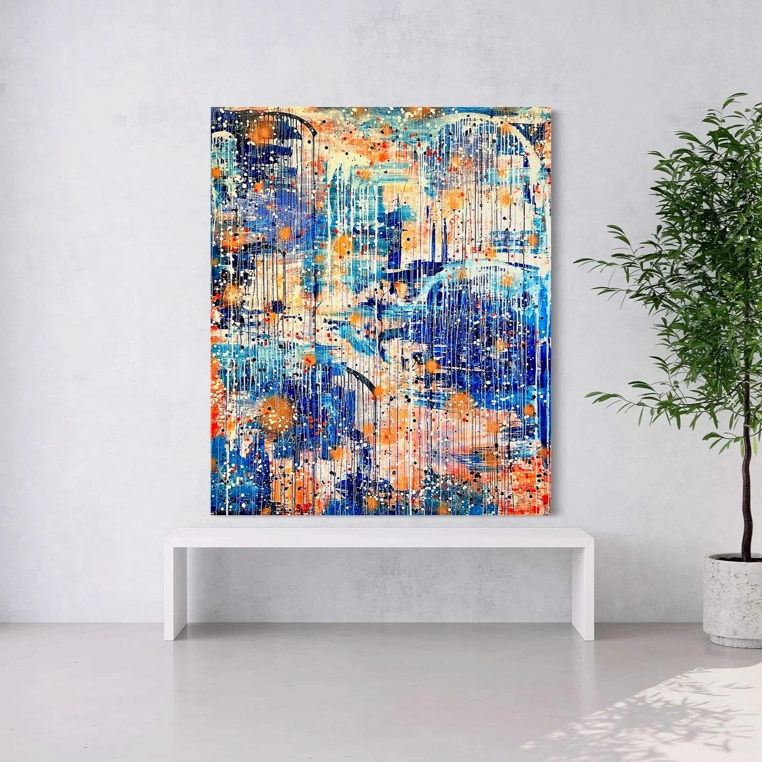 Abstract colorful artwork with drips and splatters hanging on a white wall in a modern, minimalist room with a large potted plant and a window showing a green landscape outside.