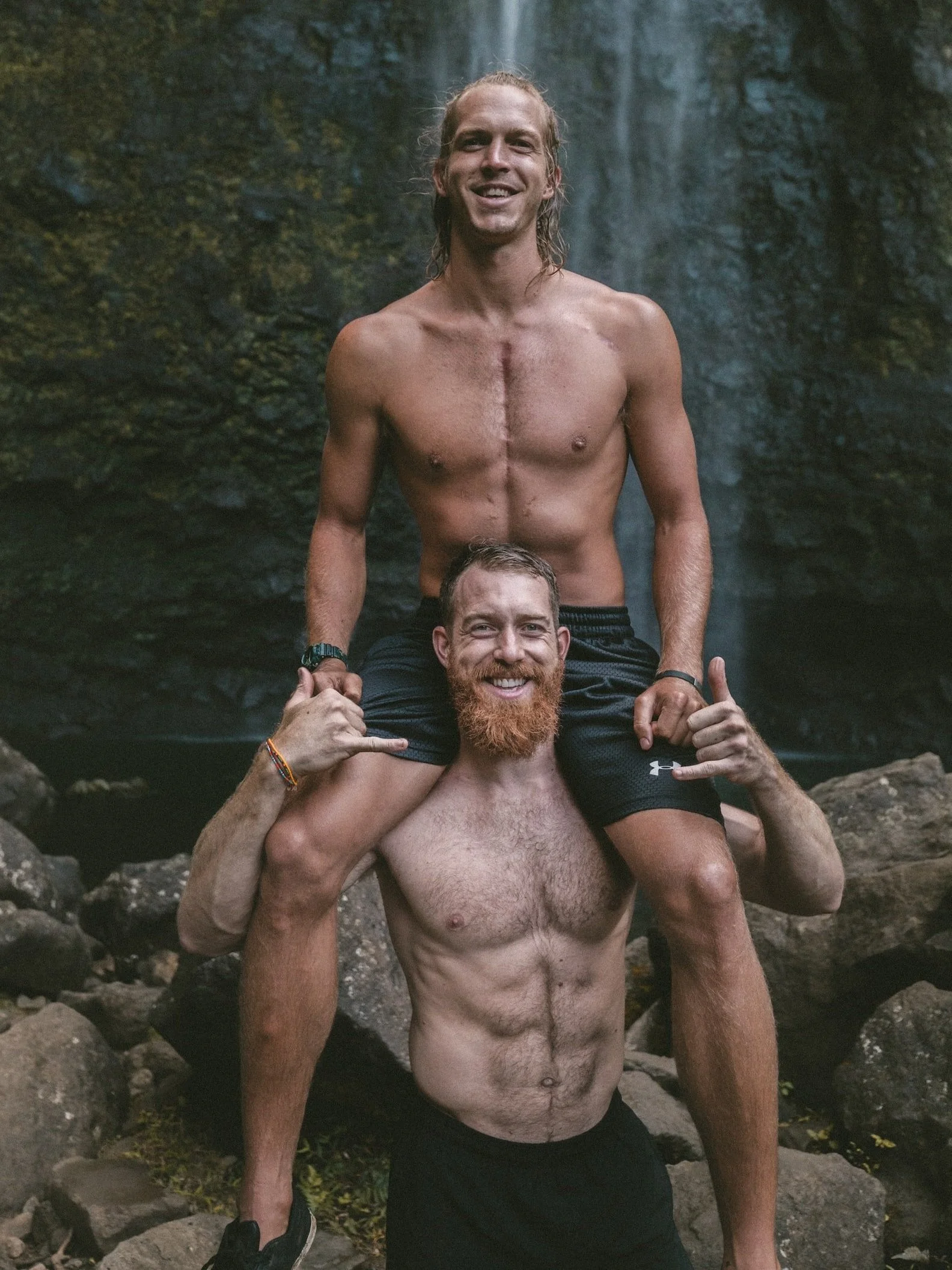 Trevor James standing at a tropical waterfall during an outdoor fitness adventure, promoting health, wellness, active living, travel, and personal growth.