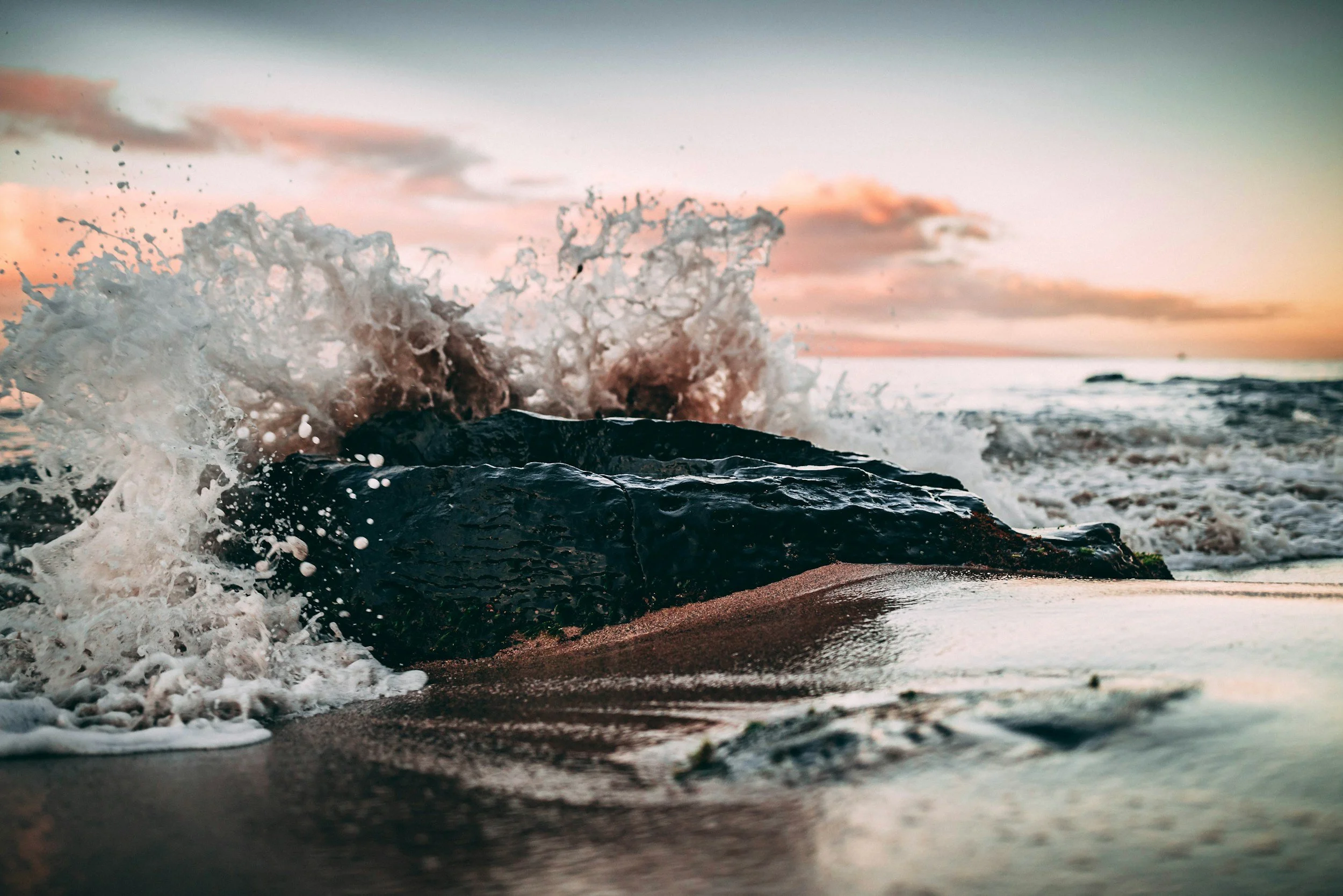 Waves crashing on rocky shore at sunset