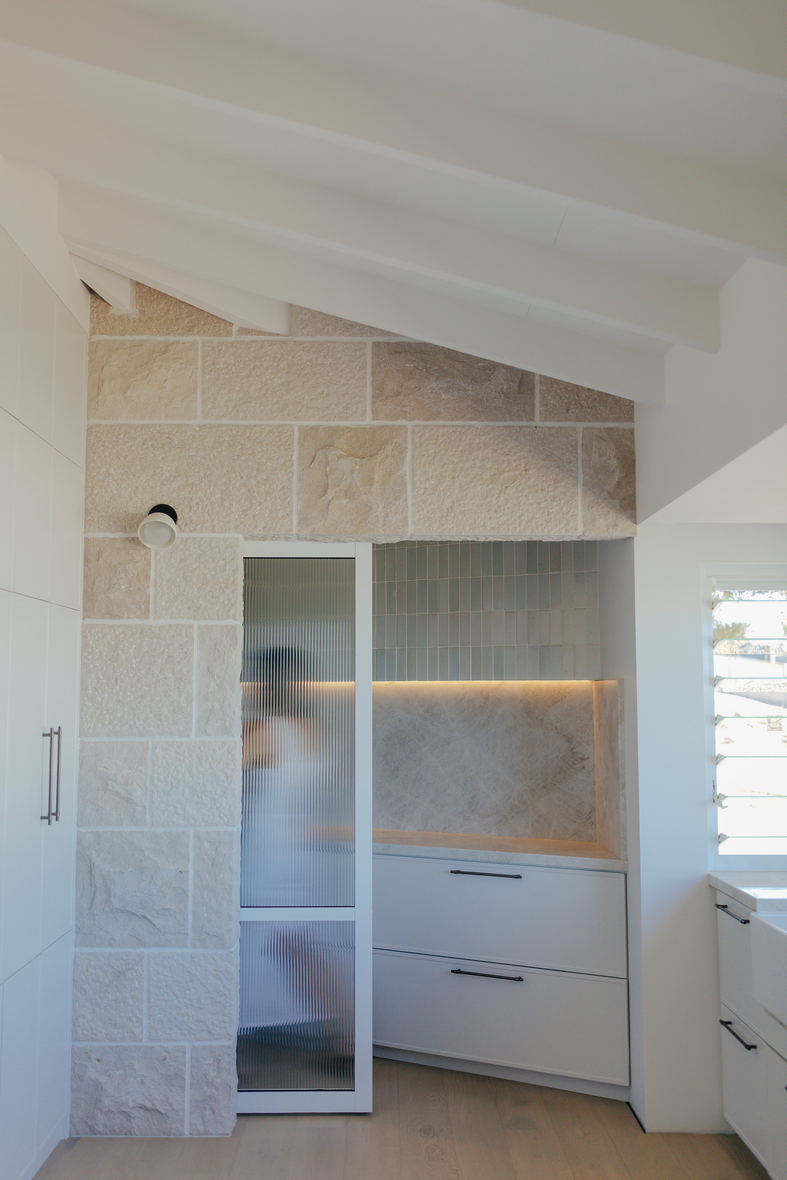 White and limestone coastal kitchen with zelliage tiles, bronze brass handles, Taj Mahl quartzite bench tops and louvre windows