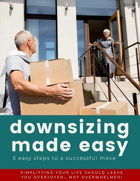 An elderly man holding moving boxes standing outside a house on the front steps, greeting a smiling woman at the door.