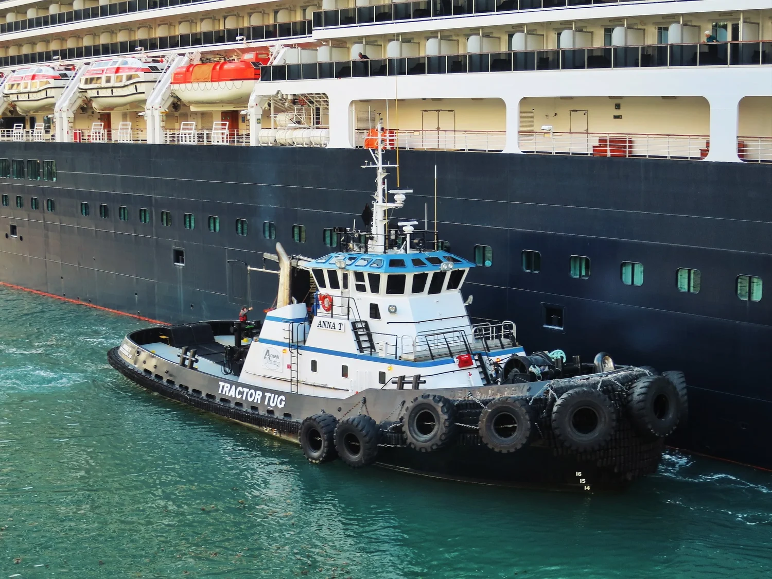A tugboat helping guide a larger vessel