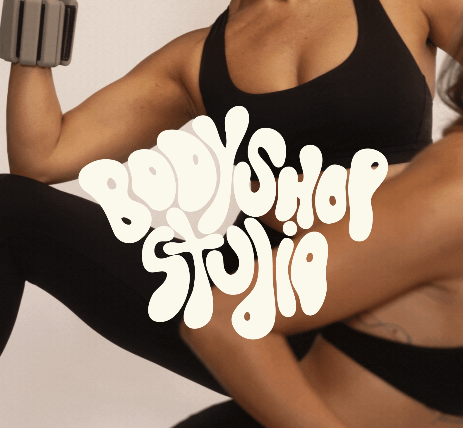 A person in black sportswear flexing their bicep muscle with an arm band, with the words 'Body Shop Studio' written in stylized text over the image.