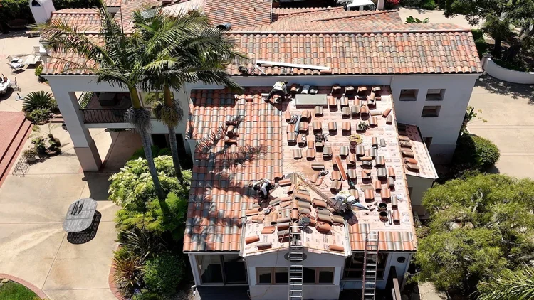 Crew relaying clay tile on a palm-lined Santa Barbara home