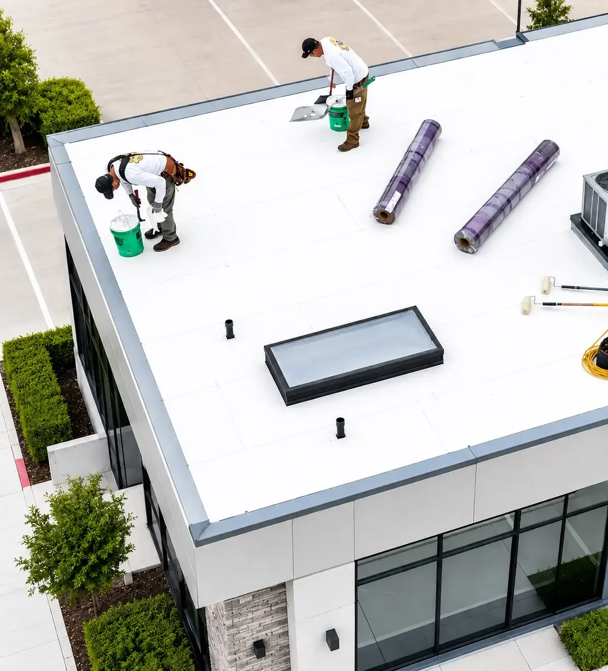 Two roofers performing commercial roof repair on a flat white roof system in Santa Barbara.