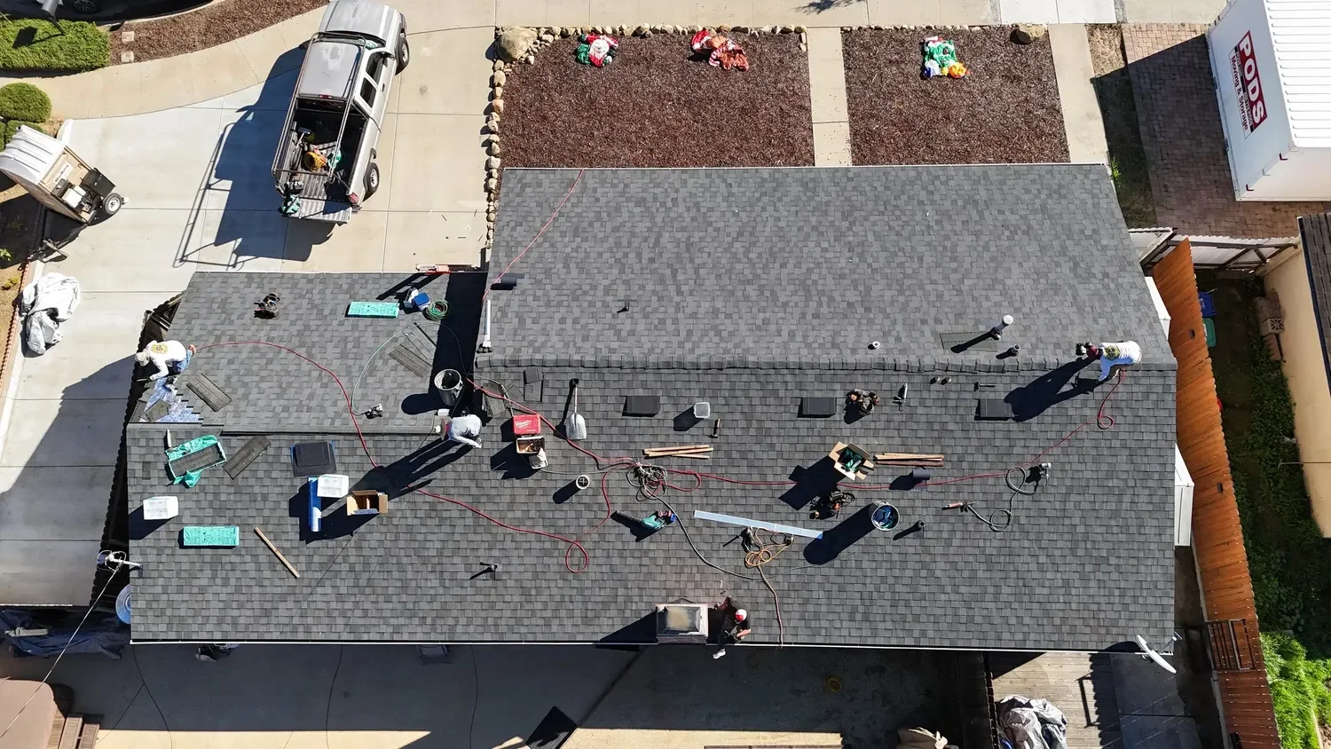 Aerial view of a full reroof in progress on a residential dark asphalt shingle roof.