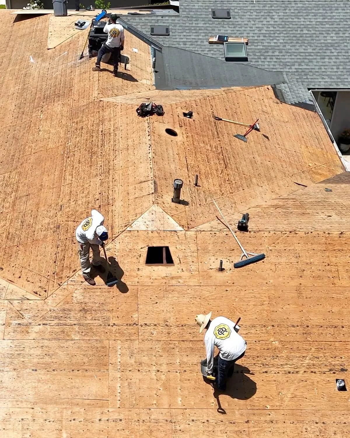 Roofing crew inspecting and preparing roof decking during a Santa Barbara roof replacement for proper code-compliant installation.
