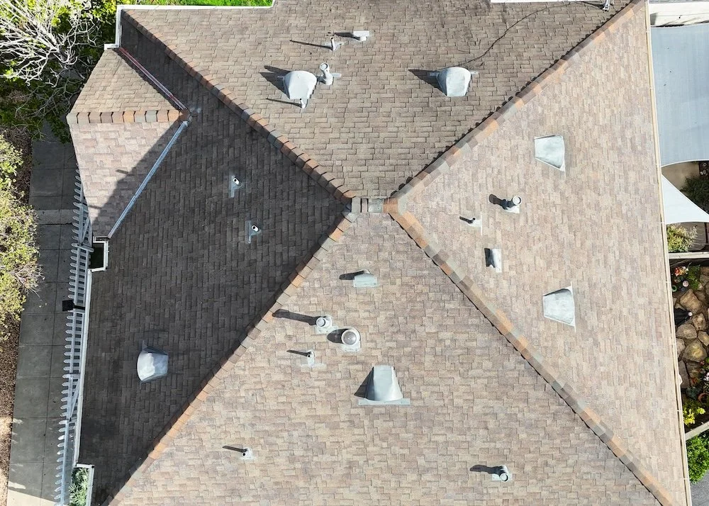 Drone view of a completed asphalt shingle roof replacement with new vents and flashing on a residential home in Santa Barbara, California.