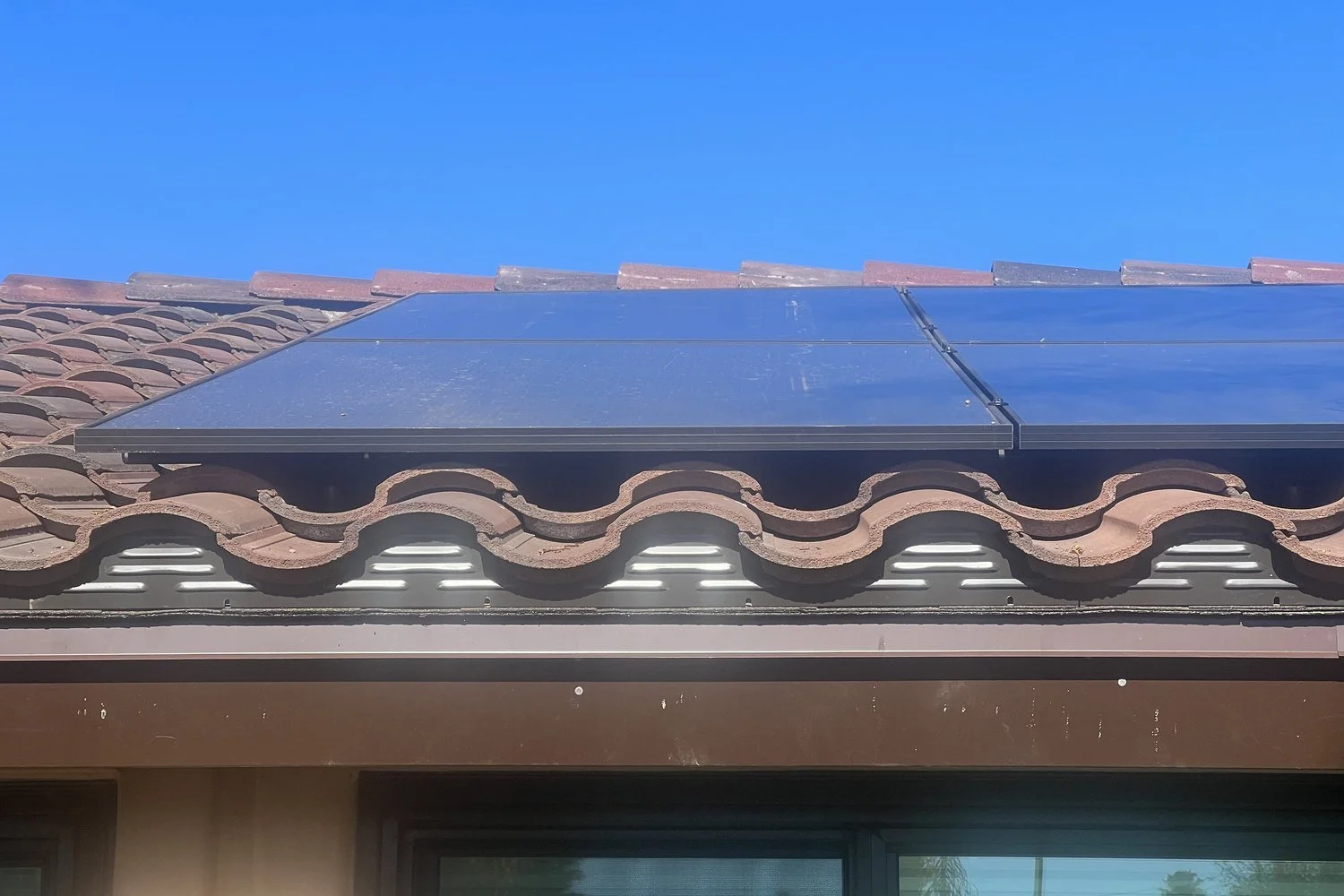 Solar panel edge mounted above the eave of a clay tile roof