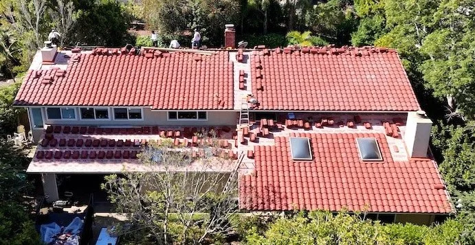 Drone view of a roofing crew installing new red concrete S tiles during a roof replacement on a Santa Barbara home.