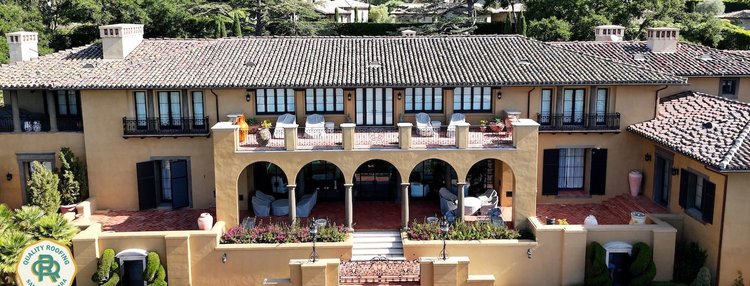 Drone view of a luxury Santa Barbara estate with an architectural clay tile roof and detailed balconies.