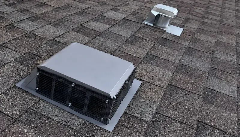 Roof vent with protective mesh over its openings on an asphalt-shingle roof 