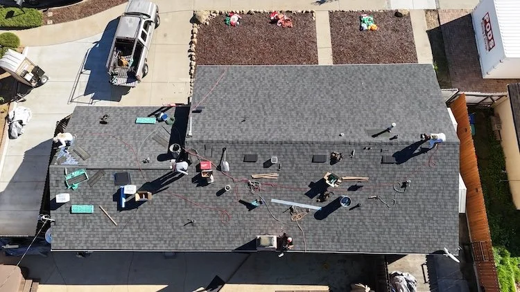 Drone view of a roofing crew in the middle of an asphalt shingle roof replacement on a Santa Barbara home.