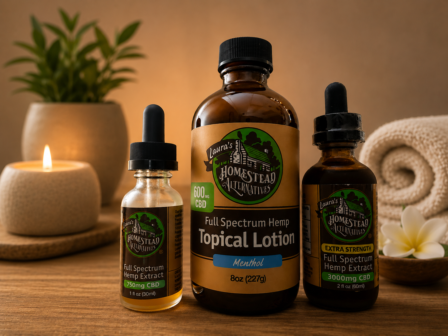 Three bottles of Laura's Homestead Alternatives CBD products on a wooden surface, with a candle, potted plant, rolled towel, and flower in the background.