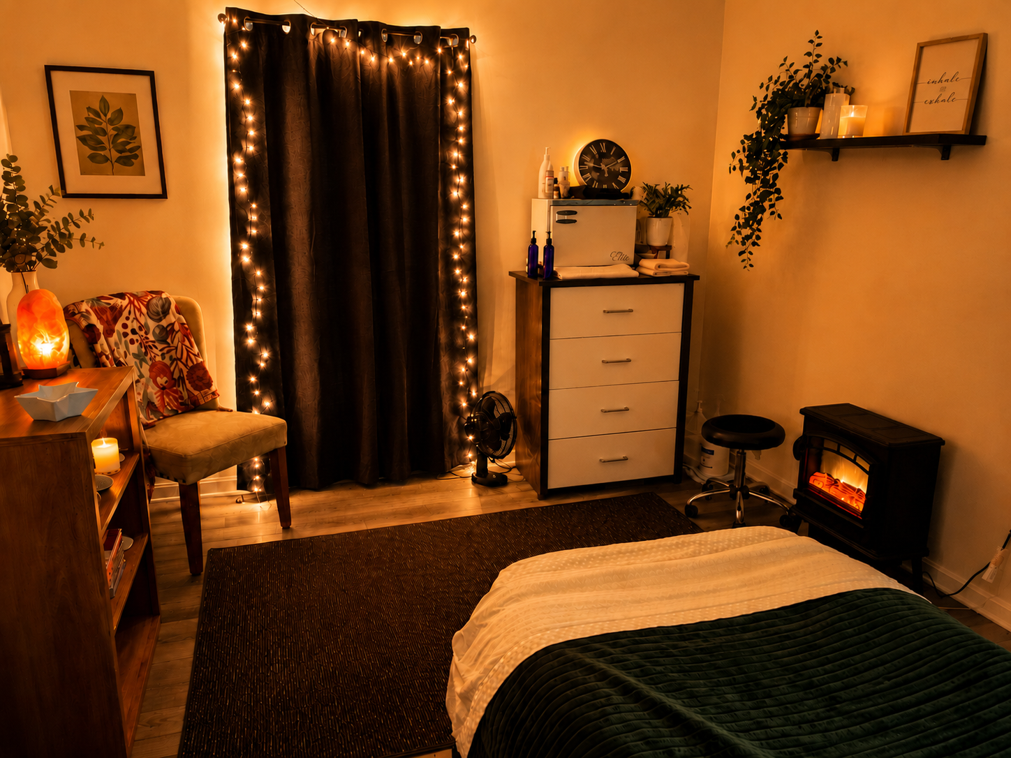 Cozy bedroom illuminated with warm, ambient lighting, featuring fairy lights on dark curtains, a bed with a black blanket and white sheet, a small heater, a dresser with decorative bottles and plants, a chair with floral cushions, a bookshelf, and wall art with candles.