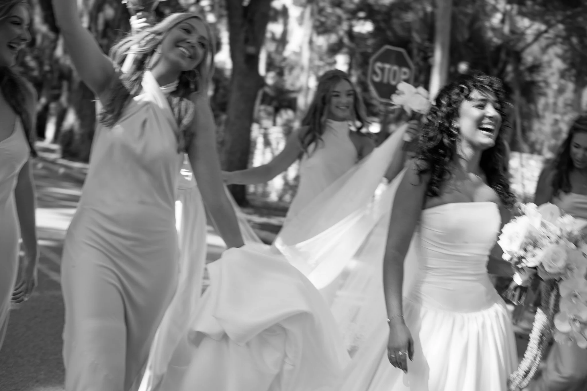 A group of bridesmaids, including a bride in a strapless wedding dress and holding a bouquet, smiling and enjoying a celebration outdoors in St. Augustine, Florida.