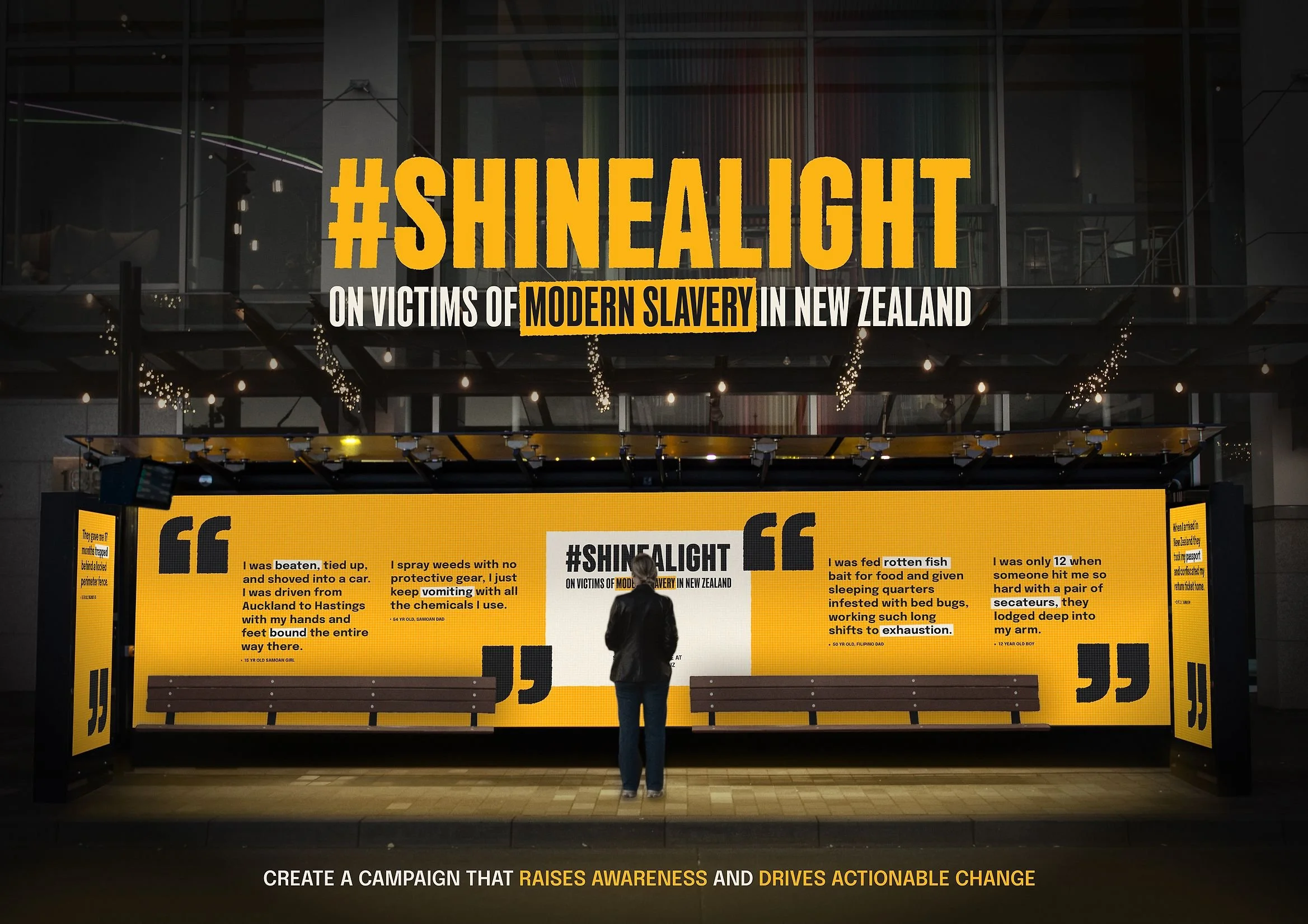 A large illuminated billboard with campaign messages and quotes addressing victims of modern slavery in New Zealand. A person stands in front of it, observing the display.
