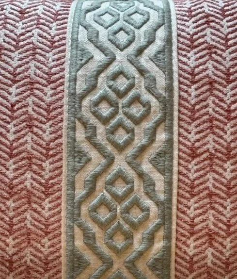 Close-up of a decorative rug with a geometric pattern in shades of gray, beige, and pink.