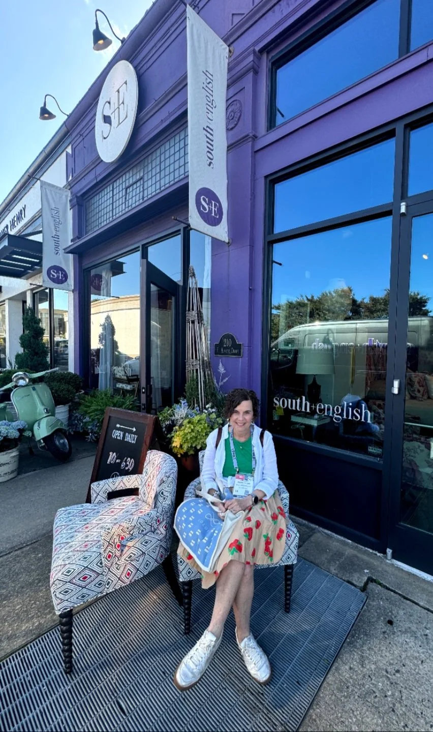A woman sitting outside a purple storefront with