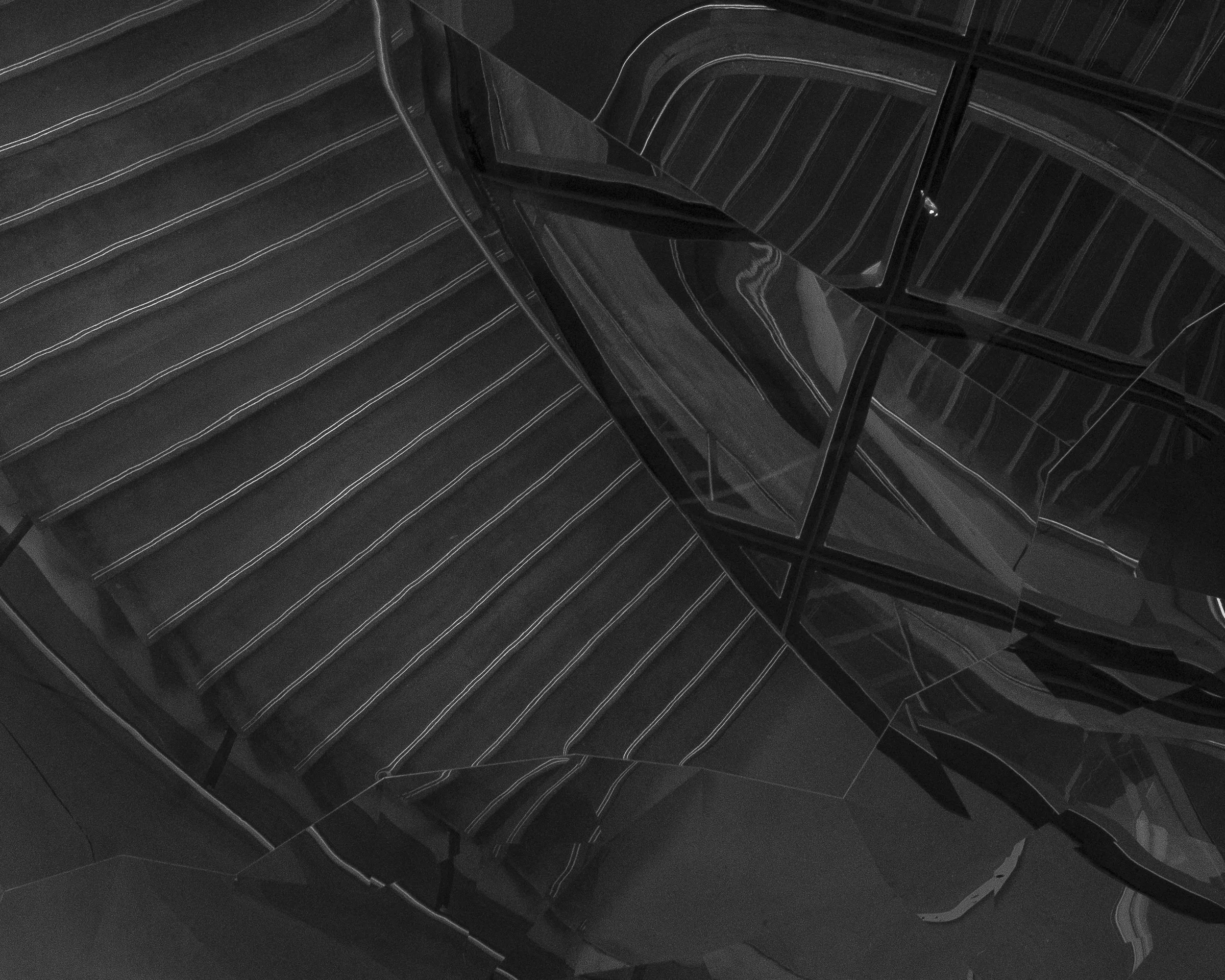 Black and white photo of a modern staircase with striped steps and reflective black panels.
