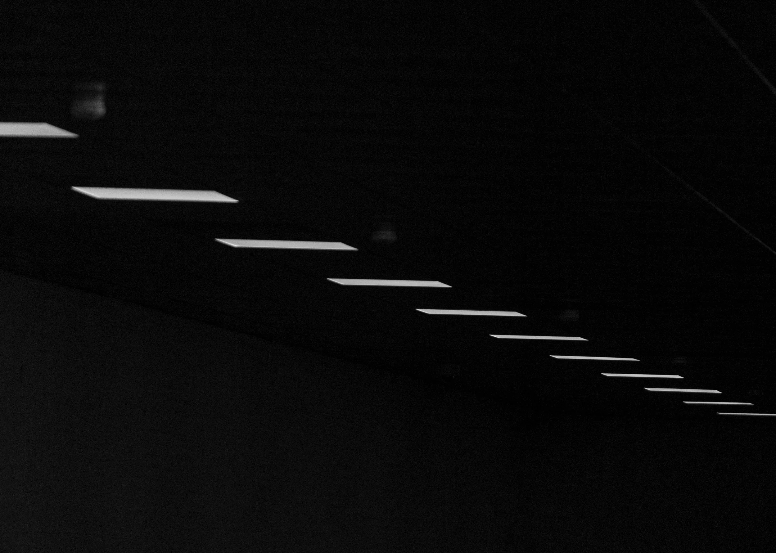 Dark ceiling with rectangular white lights arranged in a zigzag pattern.
