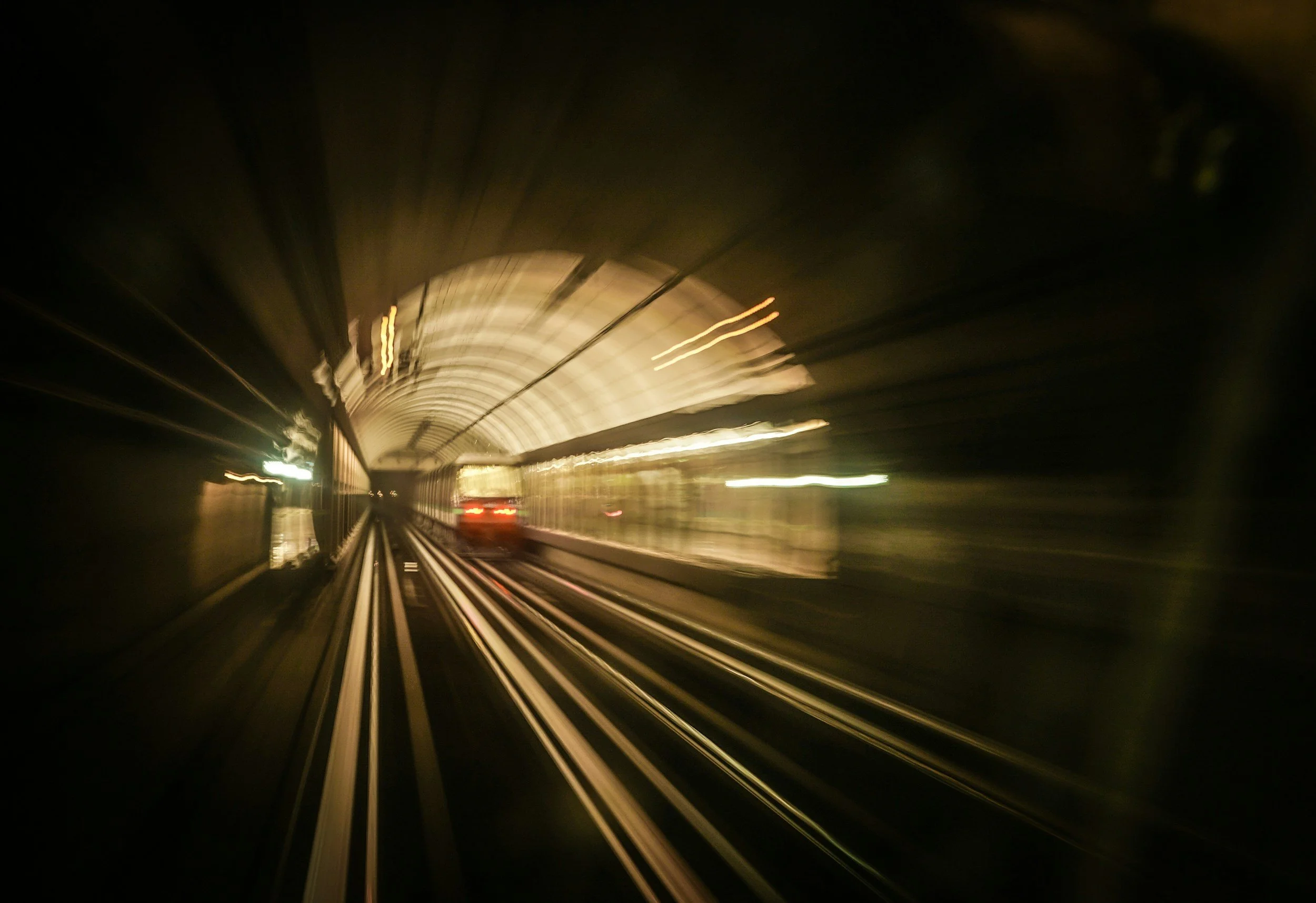 A subway train moving through a dark tunnel, captured with motion blur
