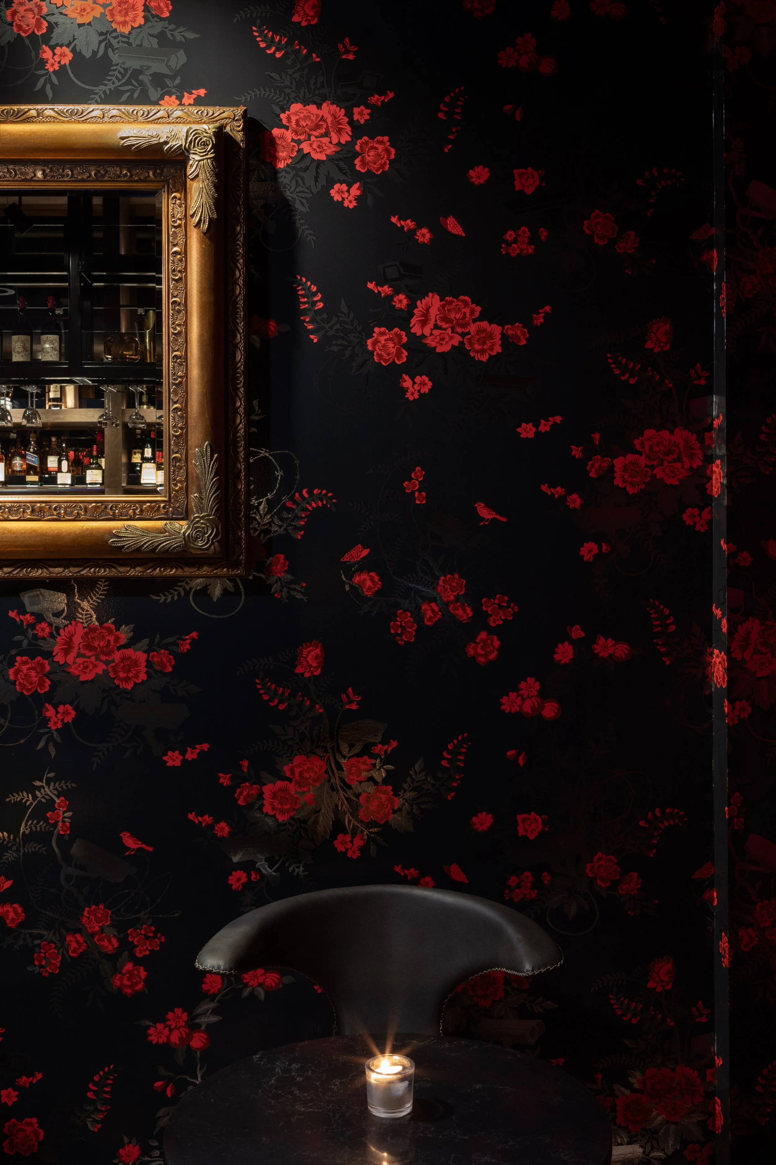Interior of Call Me Back Speak Easy in downtown Vancouver, designed by Kurtz Design, featuring a British telephone booth entrance, bold patterned tile flooring and bar front, dark floral-inspired wallcoverings, gilded mirrors, velvet drapery, feather
