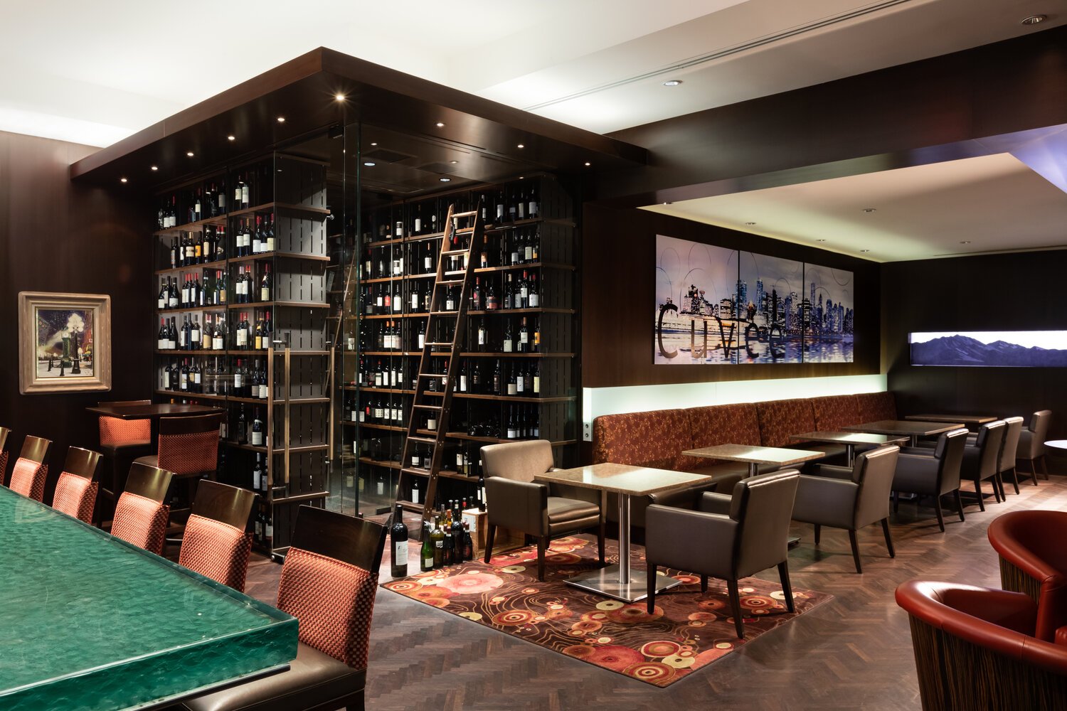 Interior design of Cuvee Wine Bar at Terminal City Club in Vancouver. Showing thick glass bar top, wine display room, seating.