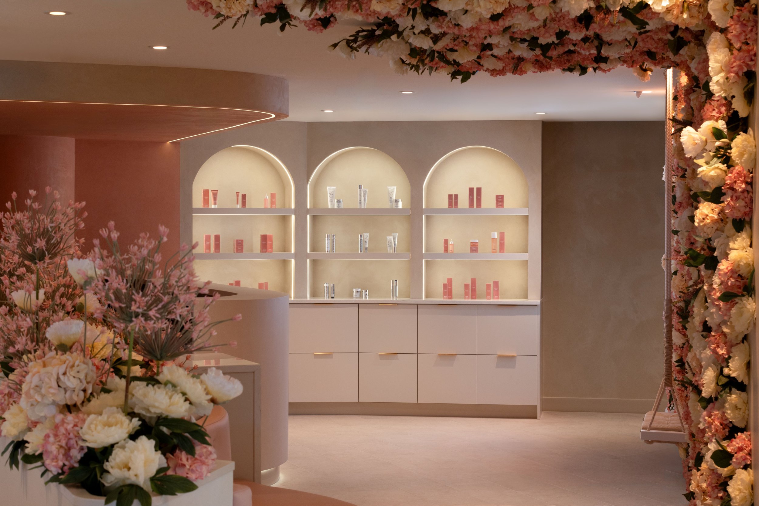 Wellness Interior design of Caviar Skin Clinic., a skin care clinic located in White Rock, British Columbia. Showing arched retail displays retail, flowers on the wall and ceiling, and pink curved custom seating.