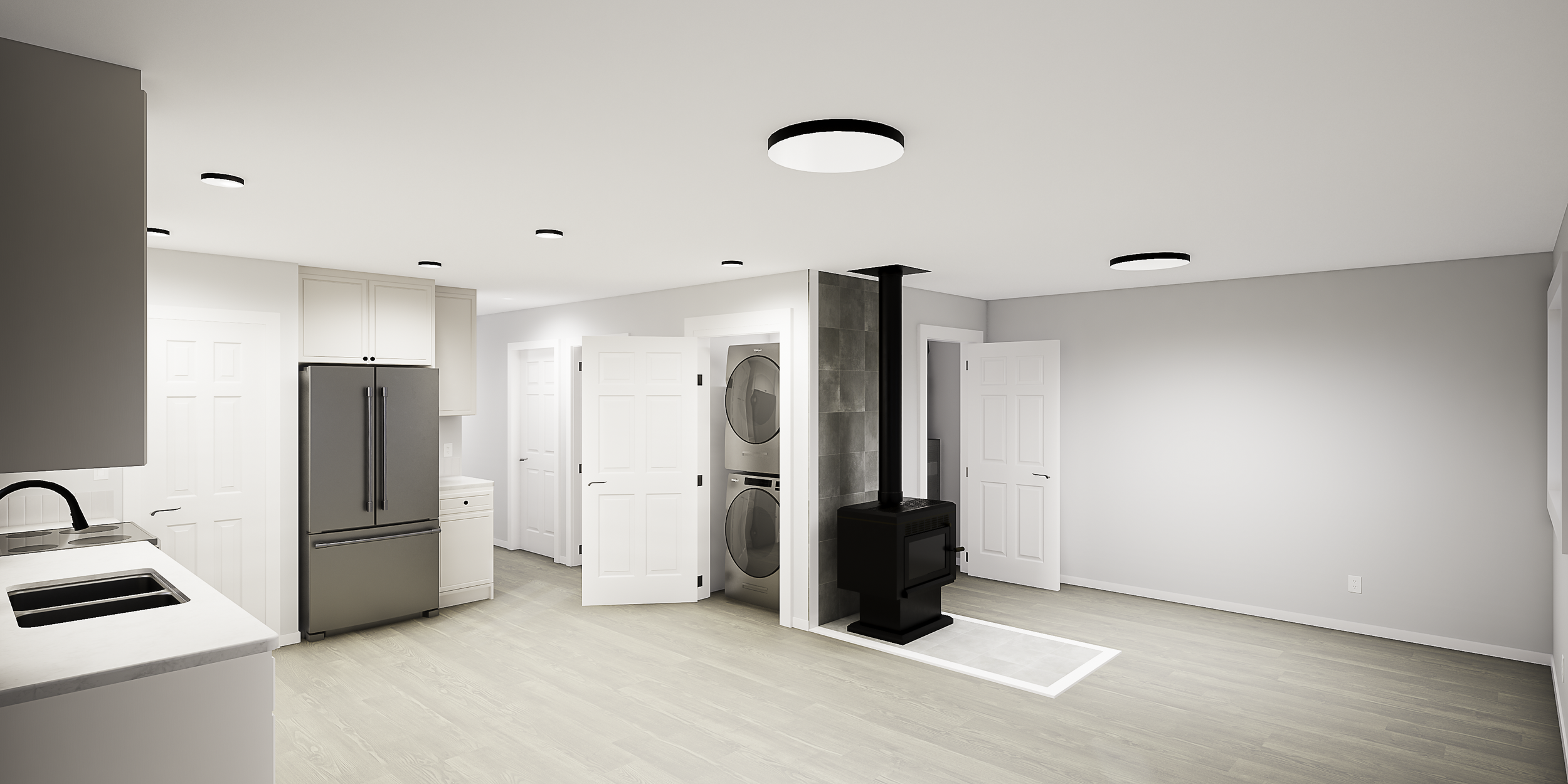 Modern kitchen with stainless steel refrigerator, white cabinets, laundry area with stacked washer and dryer, black fireplace, ceiling lights, light wood flooring, and white walls.