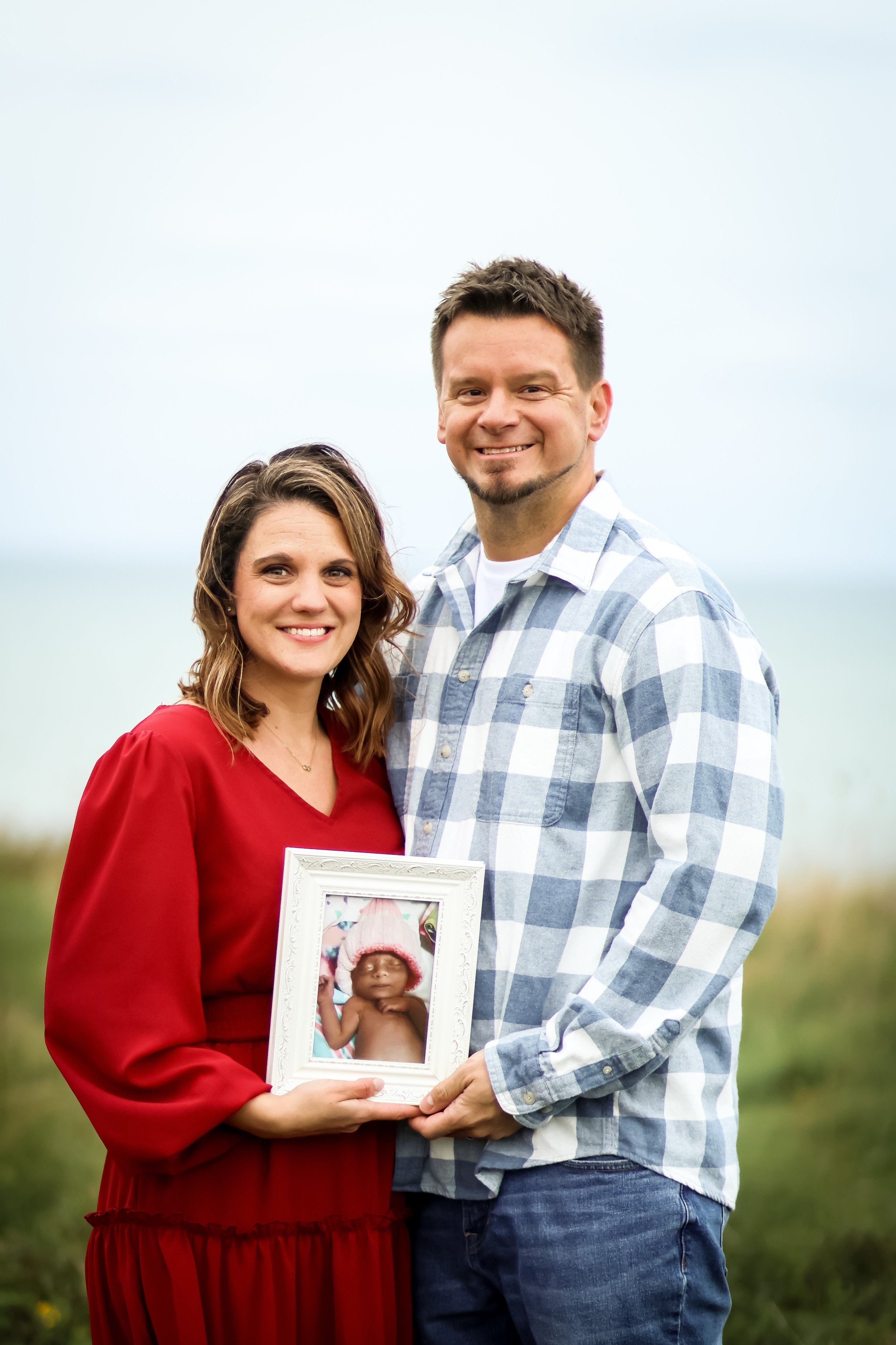 Kirstie and husband holding photo frame of Rylie Kirstie and husband holding photo frame of Rylie