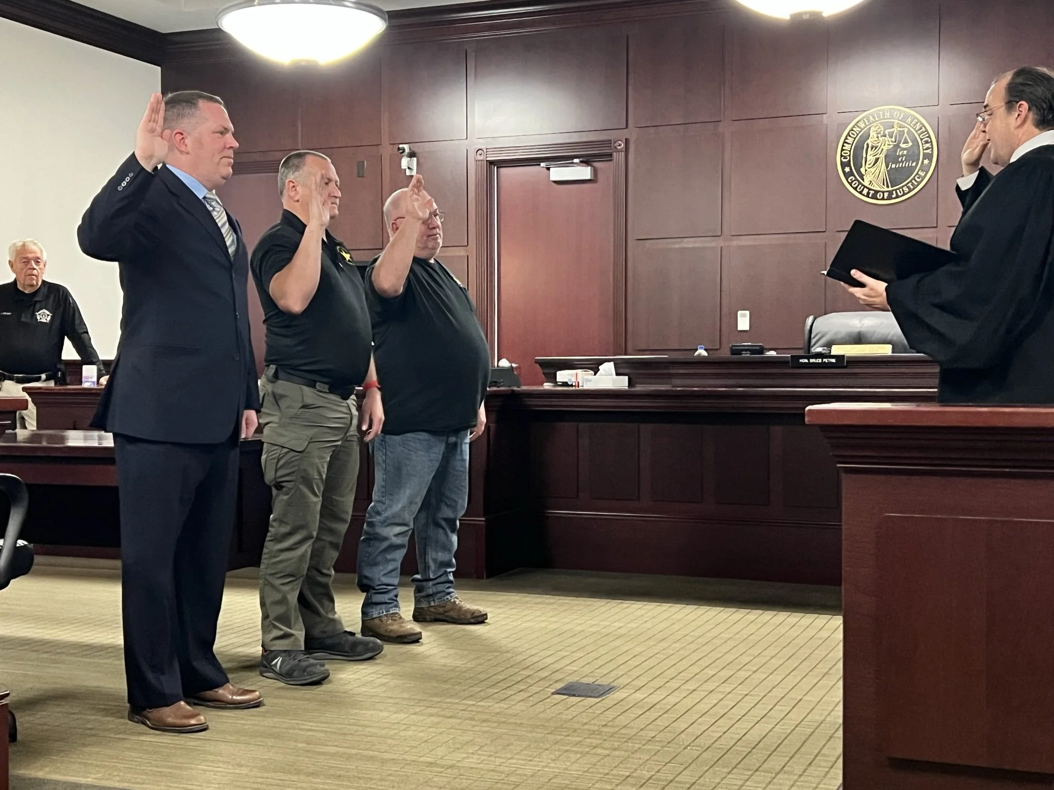 Constable Jonathan Holliday taking his oath in a courtroom, with a judge and a and two other constables in the background.