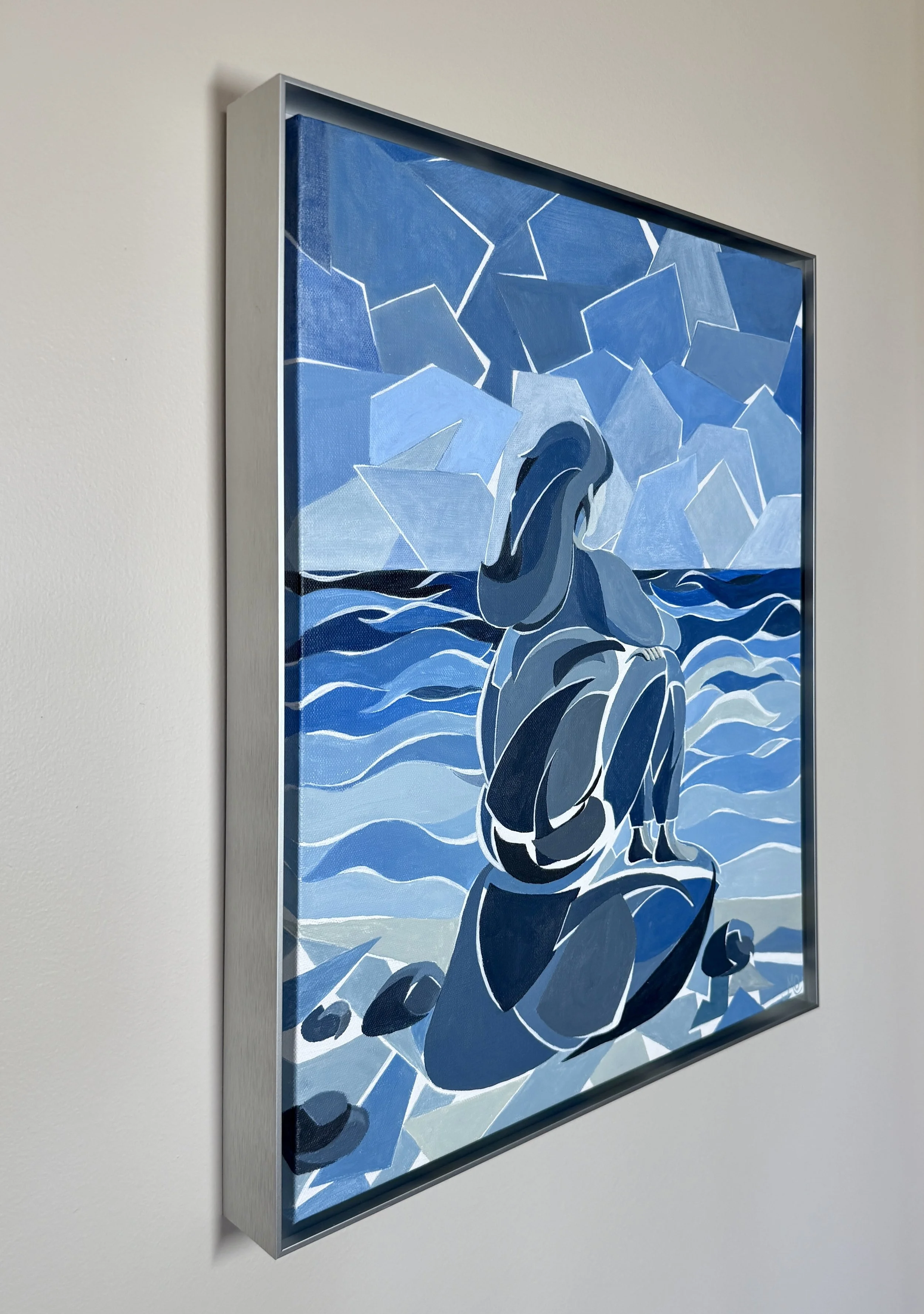 Framed painting of a woman in an elegant dress, sitting on a rock by the water, with a background of icebergs and a cloudy sky, painted in shades of blue and white.