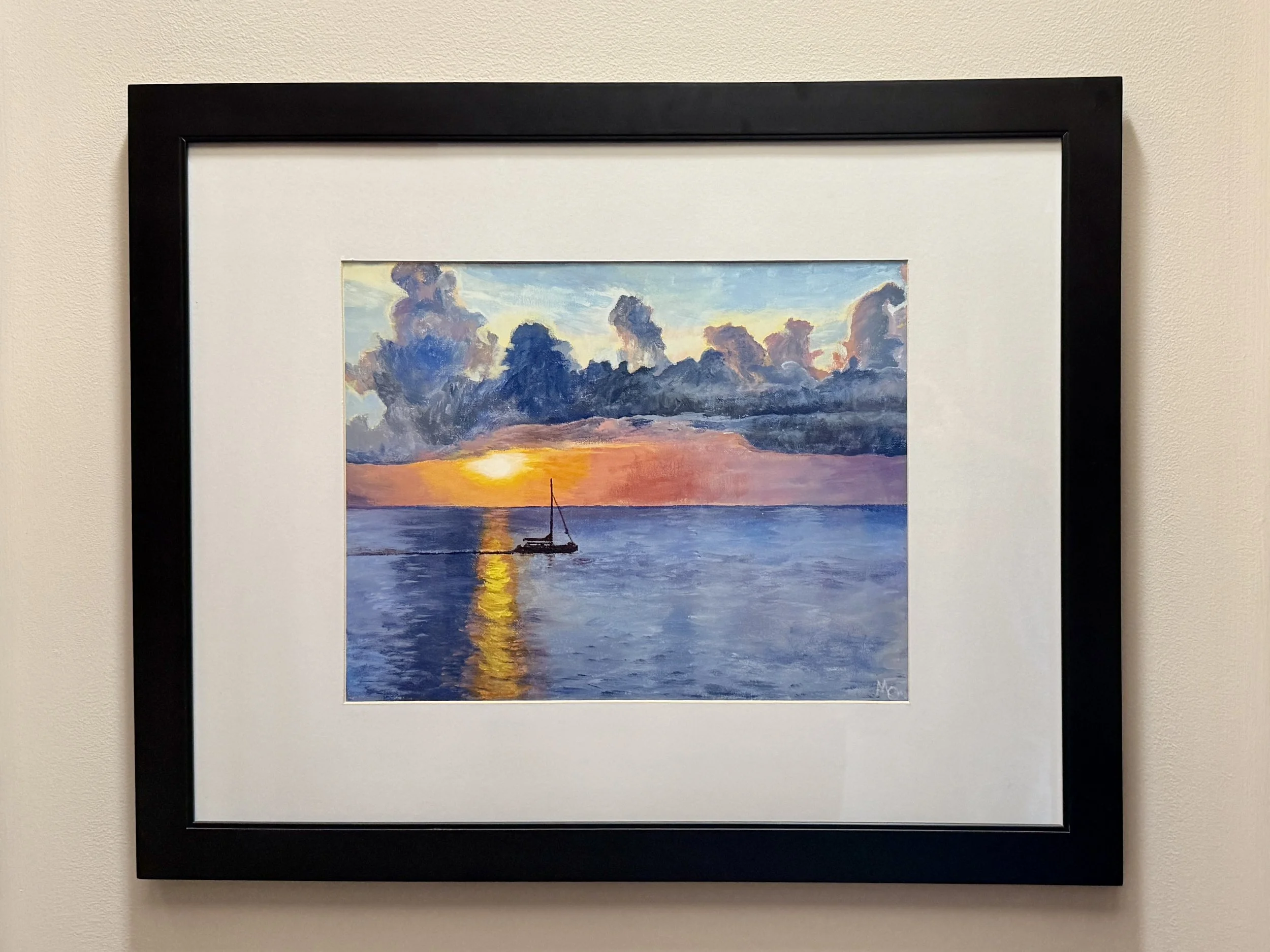 A framed painting of a sunset over the ocean with clouds and a small boat on the water.