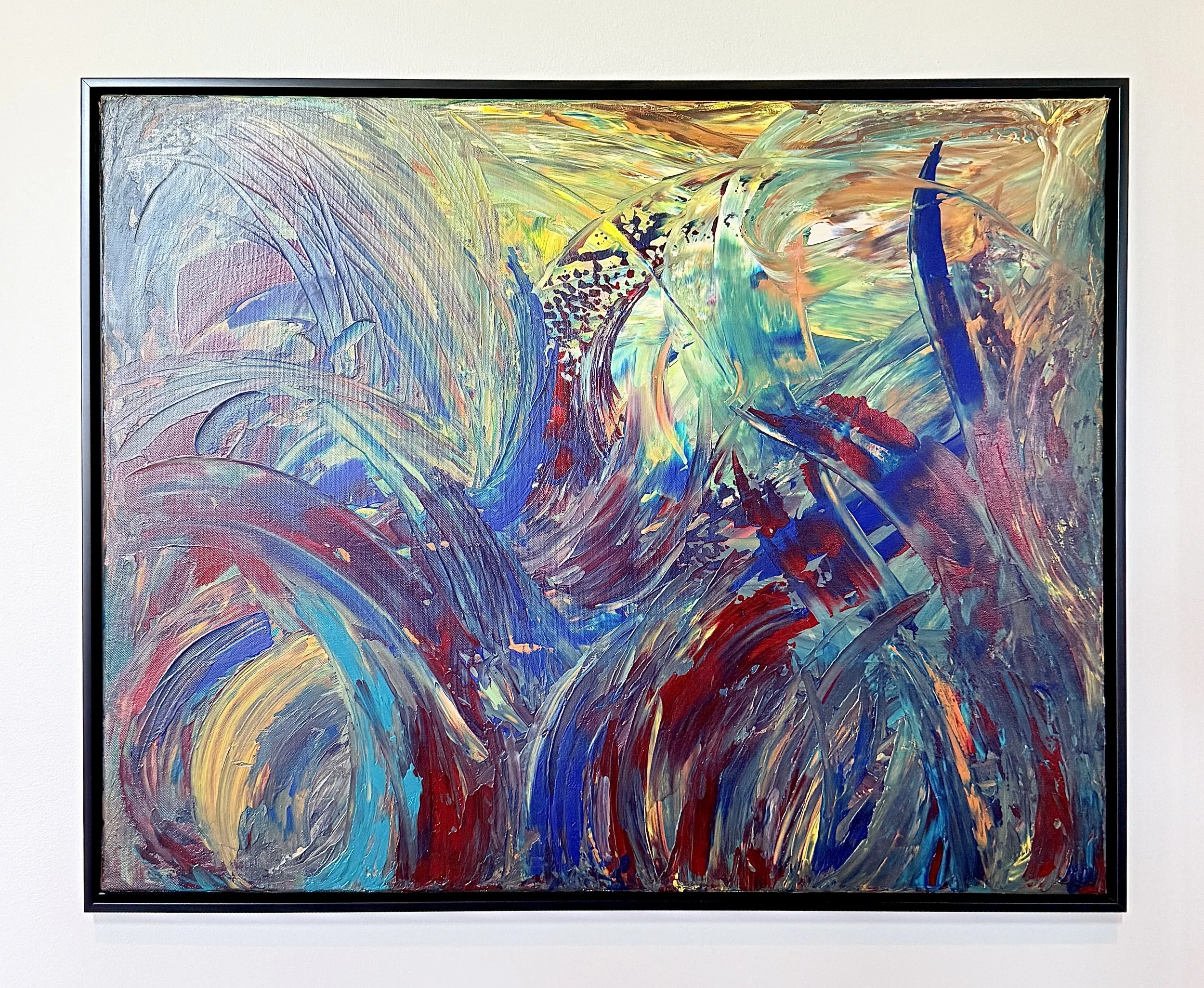 Colorful abstract painting with swirling brushstrokes in shades of blue, green, red, yellow, and purple, framed and hanging on a white wall.