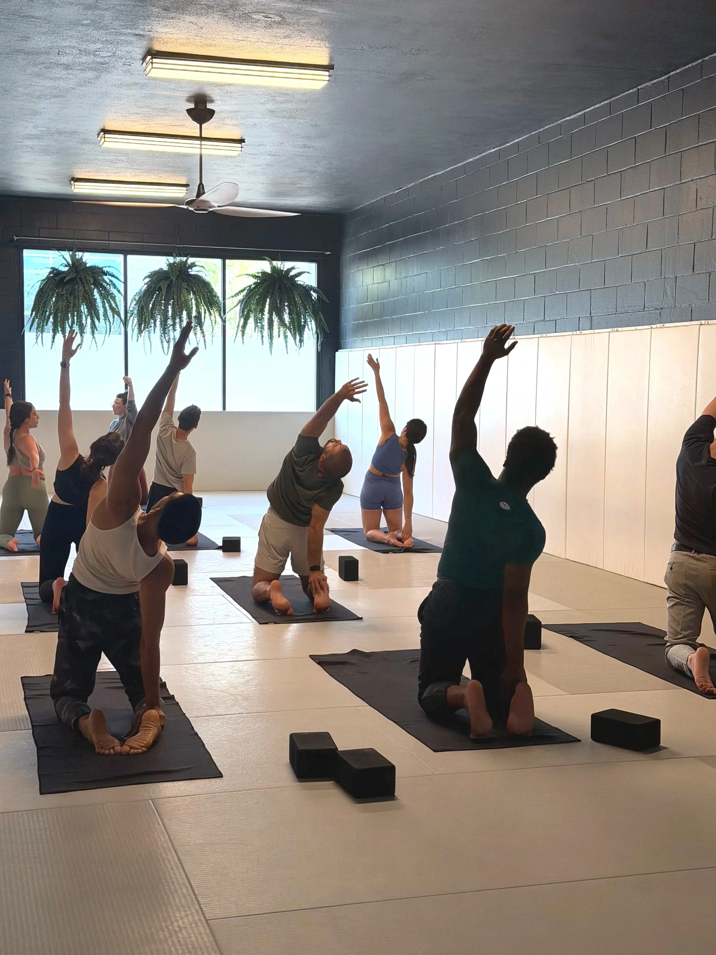 A group fitness class practicing yoga, with a trainer at the front of the room.