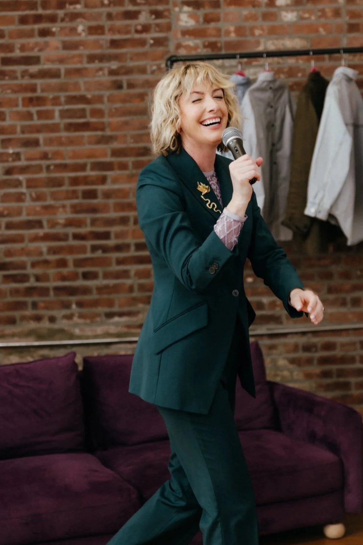 Natalie Tincher poses with a microphone before a brick wall