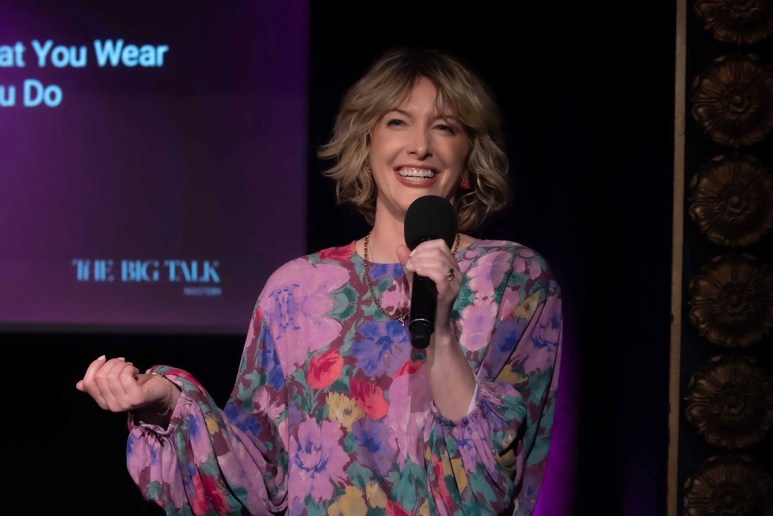 Natalie smiles on stage with a microphone