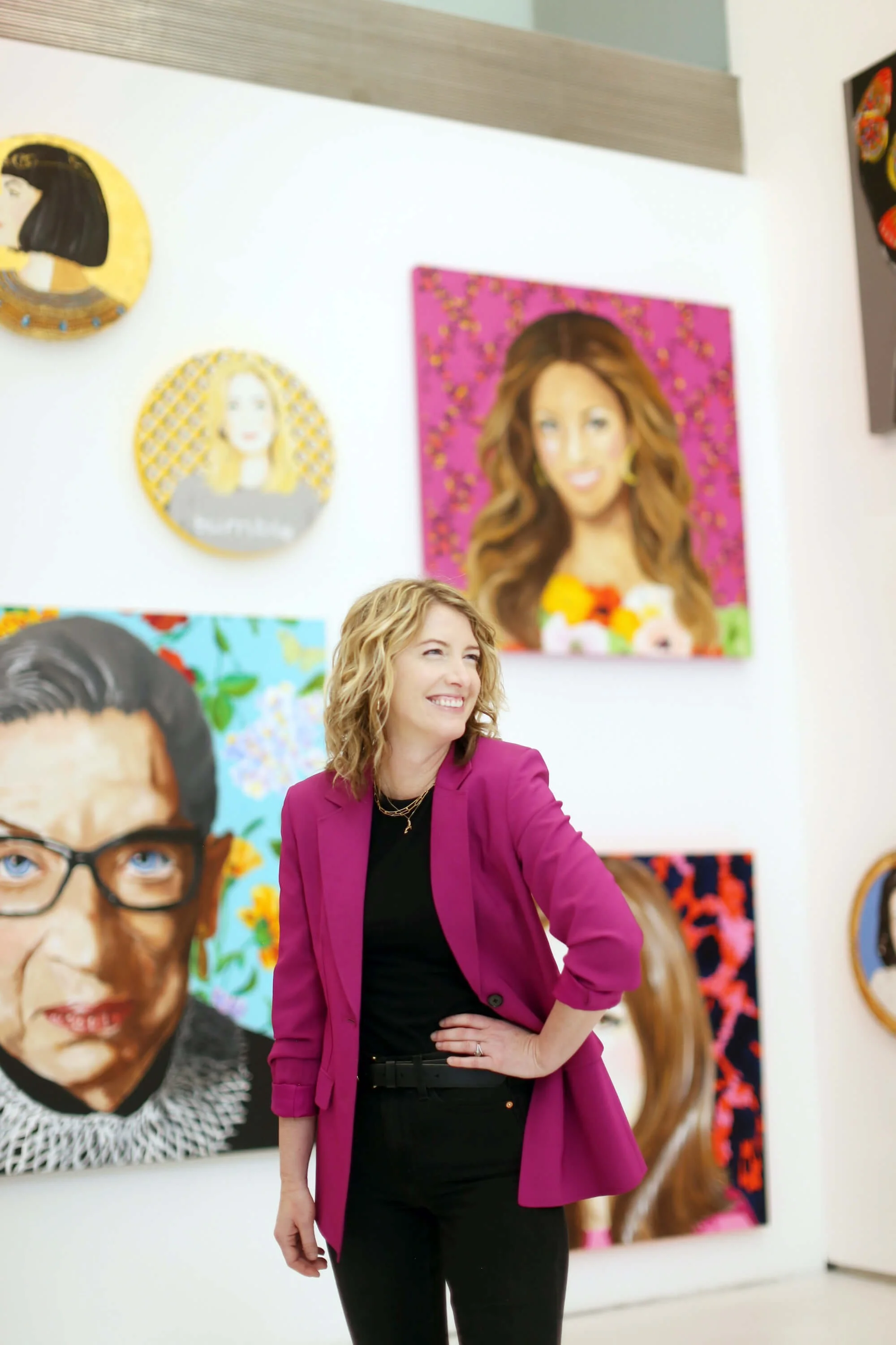 Natalie poses in a magenta blazer with a hand on her hip