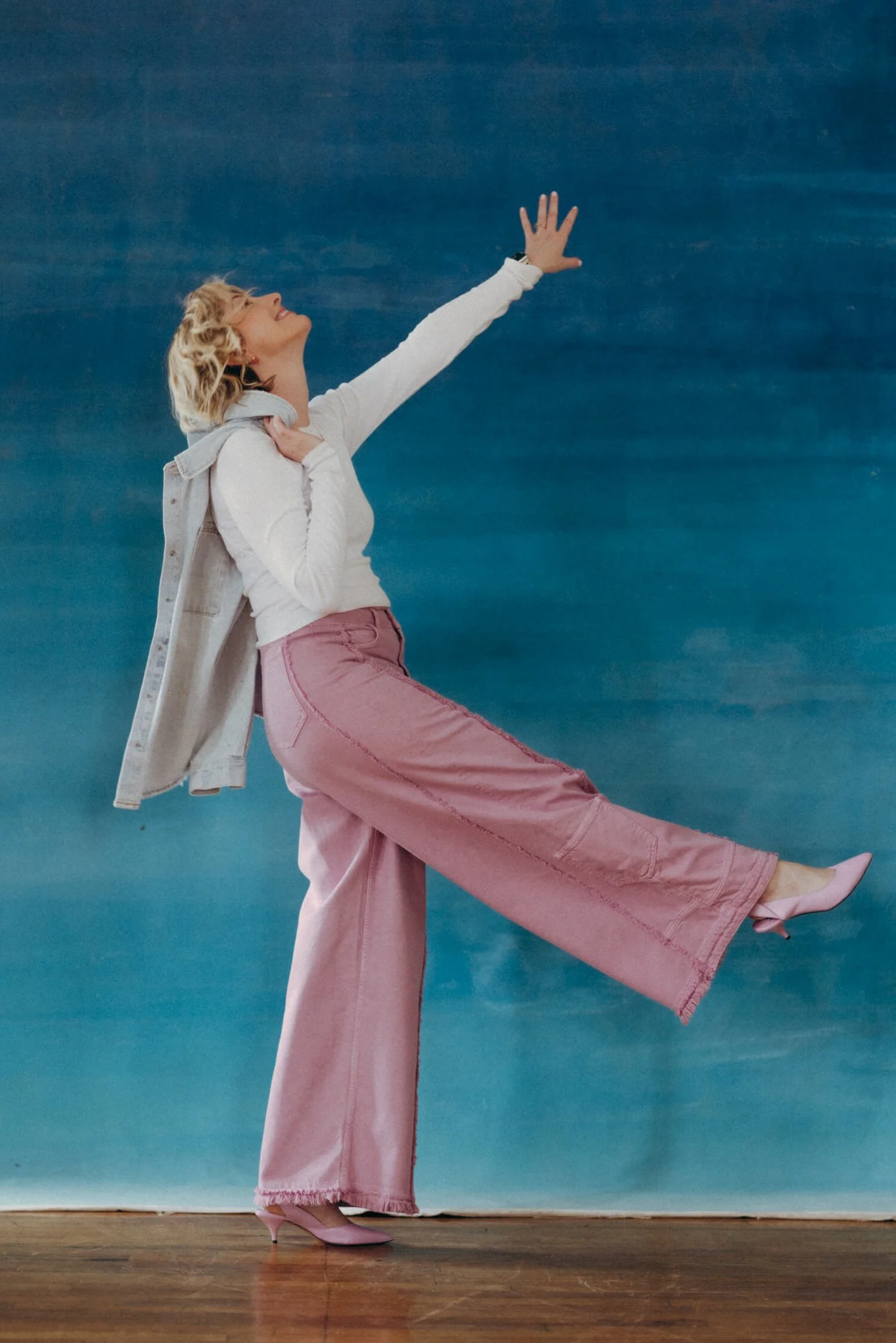 Natalie poses in pink pants in front of a blue wall