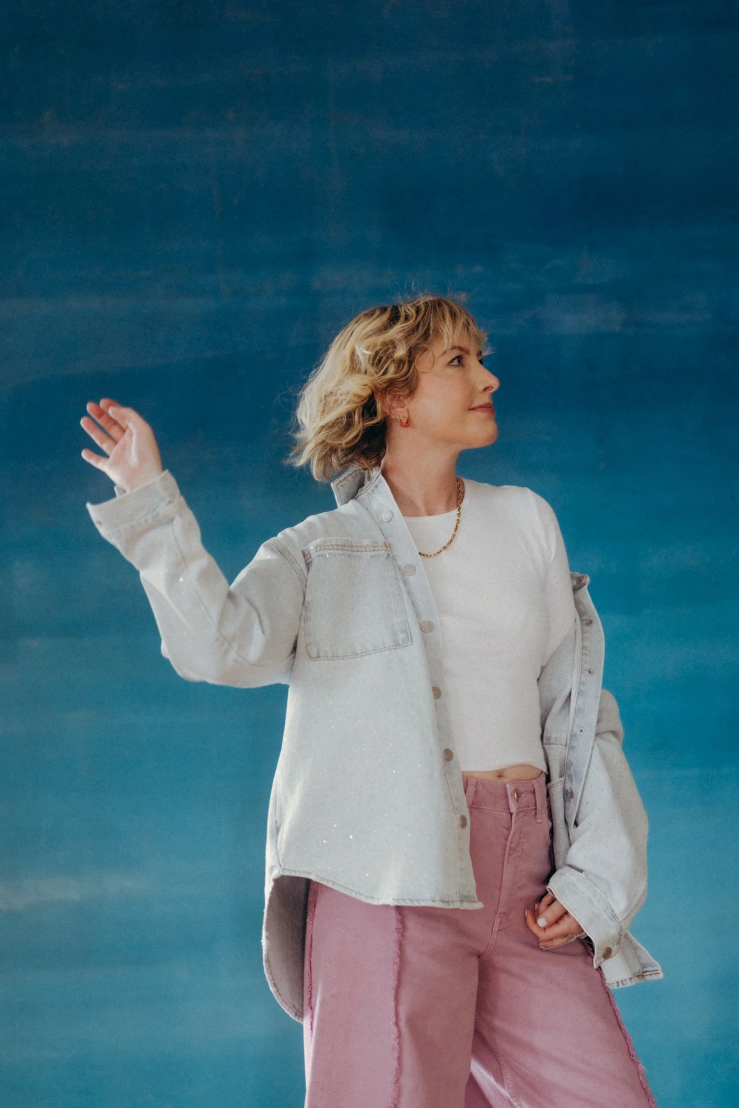 Natalie stands before a blue background, looking off to the right