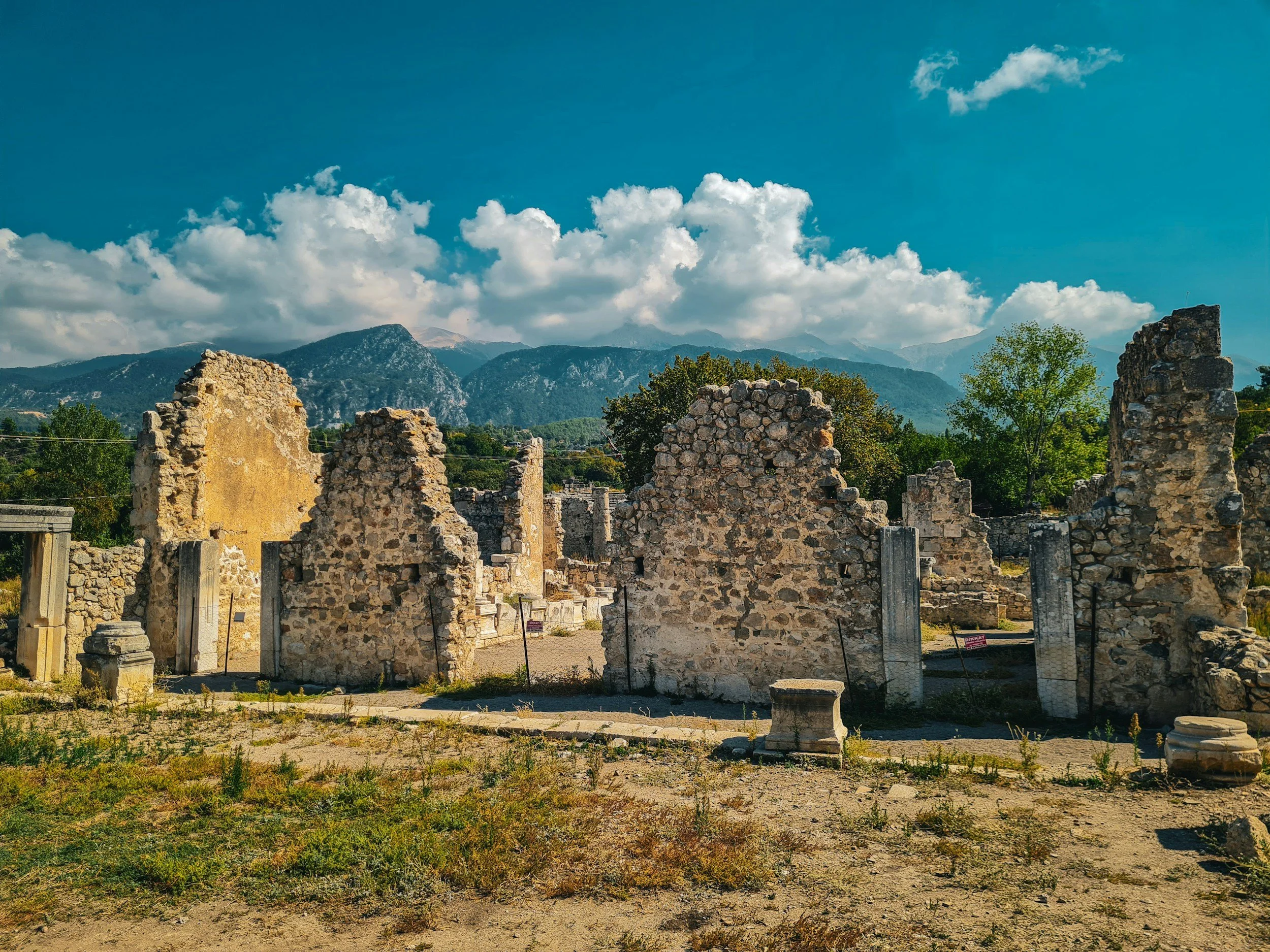 Stone ruins of the ancient oracle at Dodona in Epirus, Greece, with mountains and blue sky in the background — the oldest sanctuary of Zeus in Greek mythology