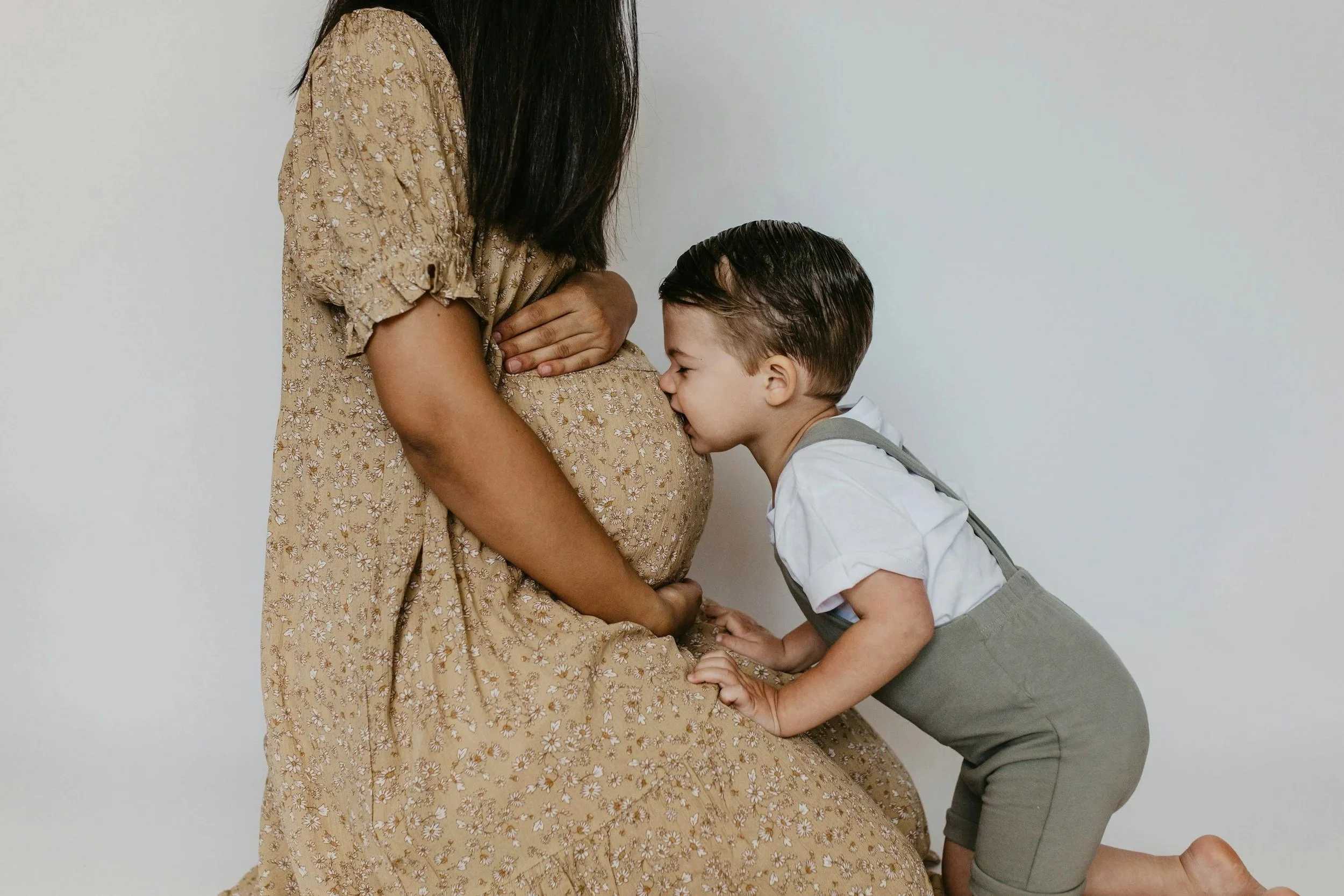 Child kissing mum's pregnant tummy